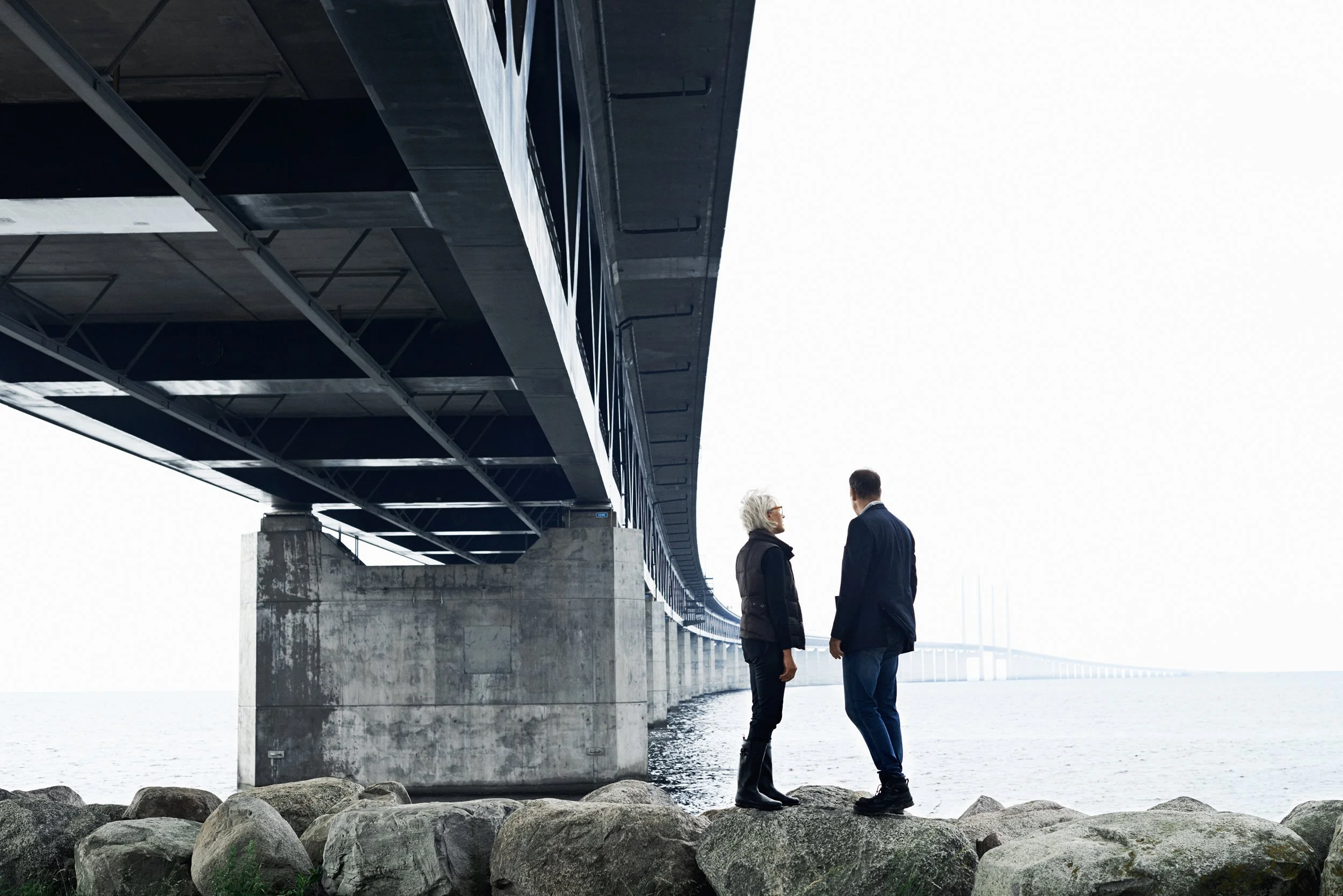 Two people standing under bridge discussing project