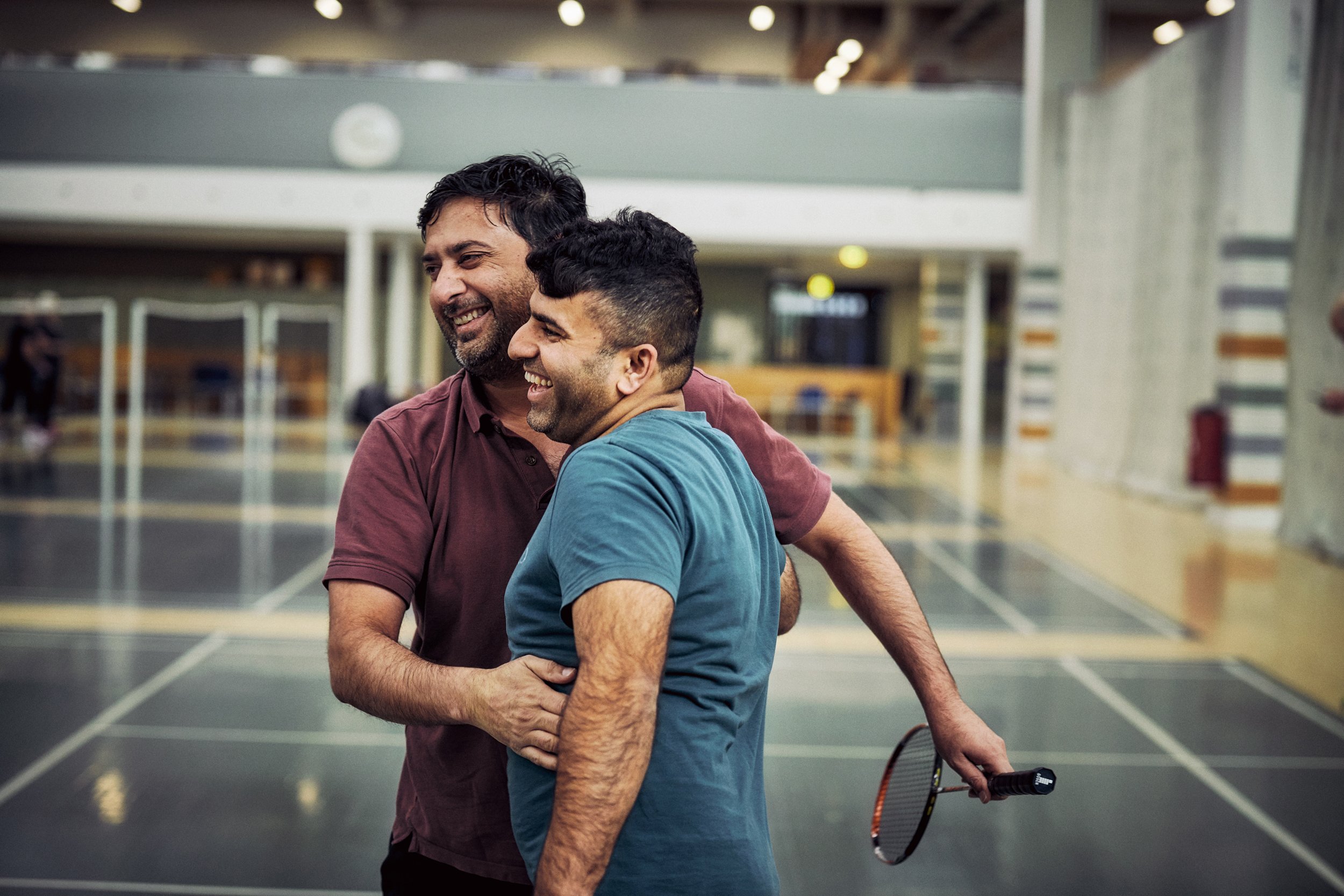 Two men interacting in sports hall, social interaction during activity