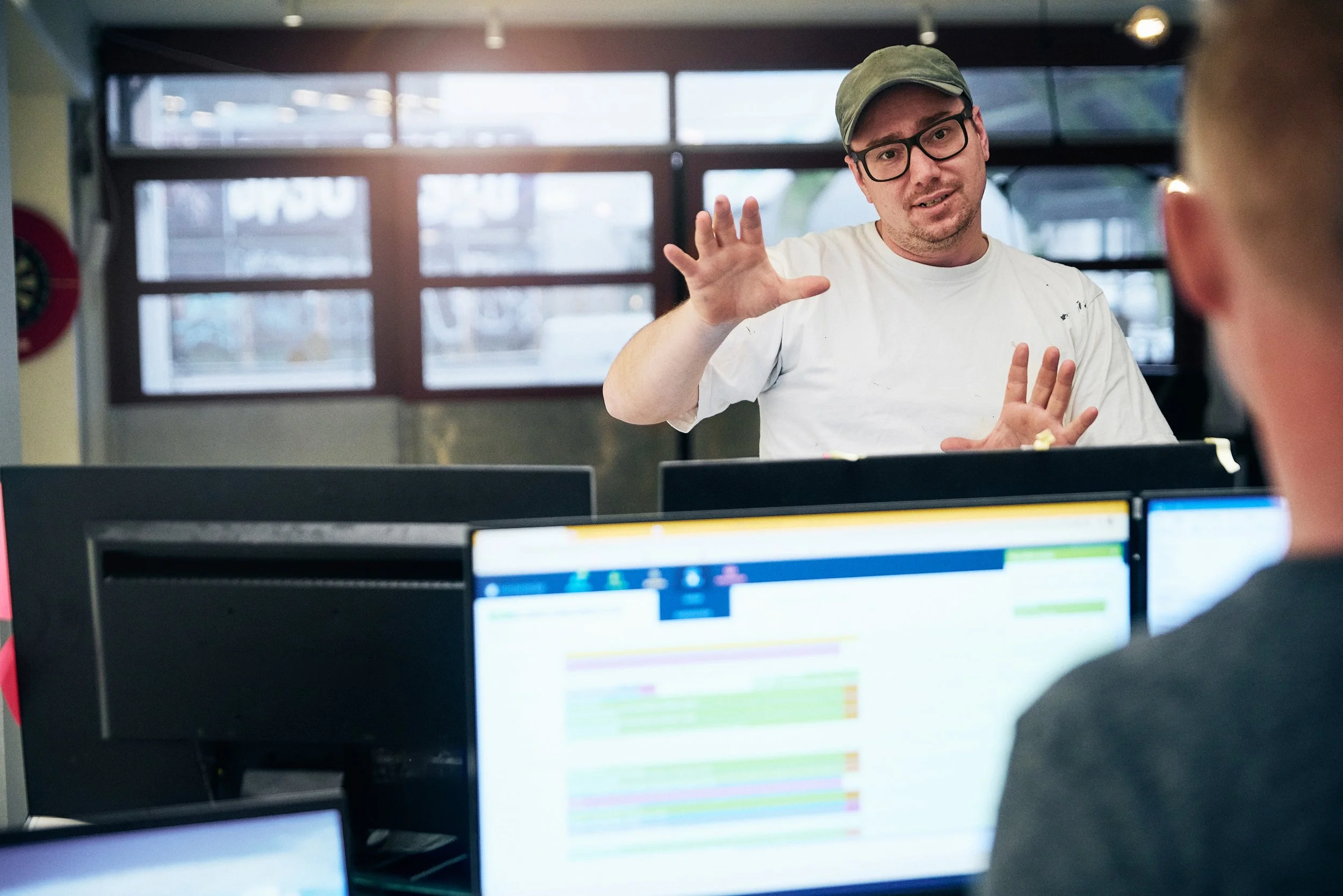 Man presenting information to colleagues across desk, workplace communication