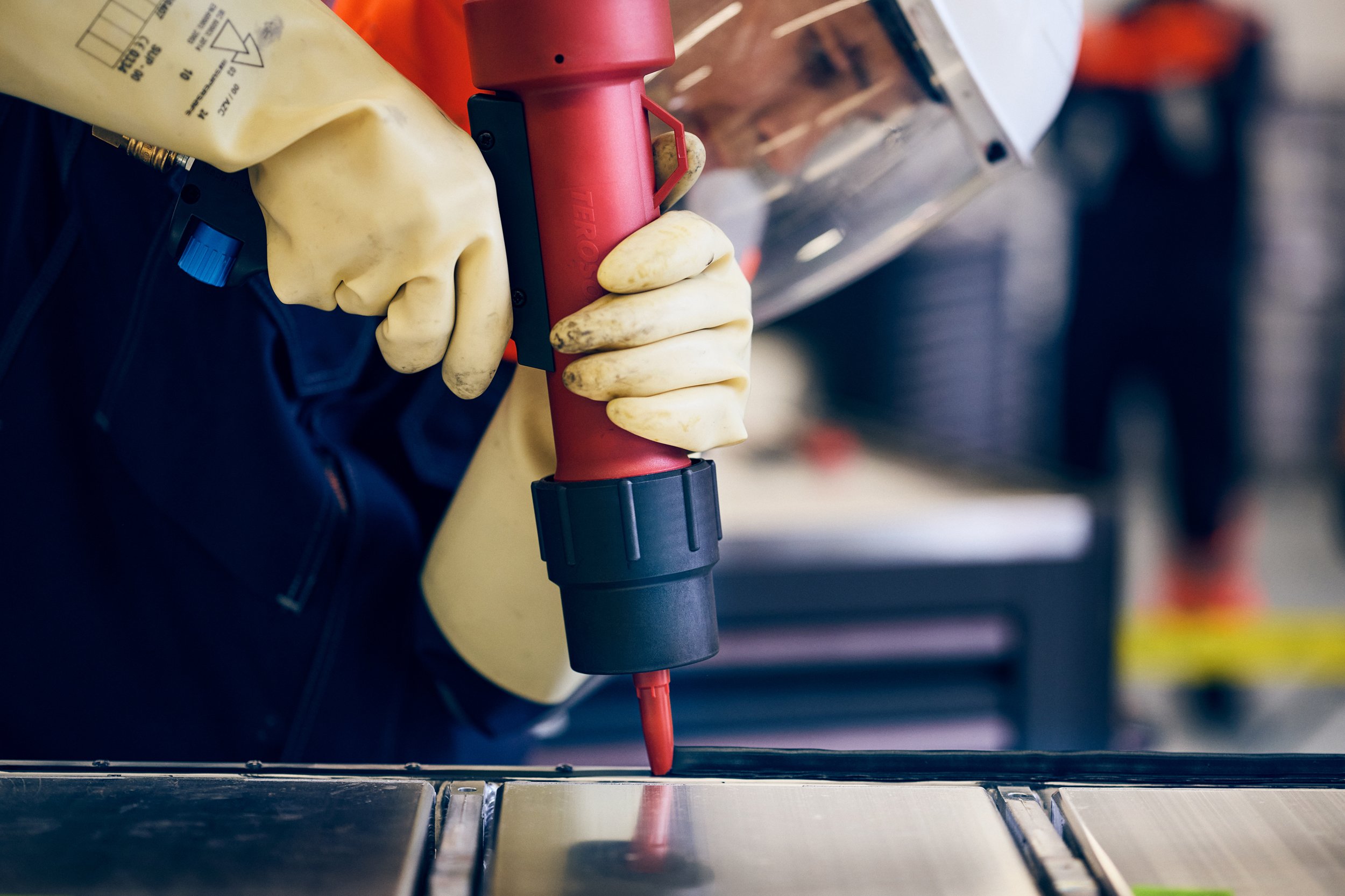 Close-up of sealant application on electric vehicle battery component, precision task