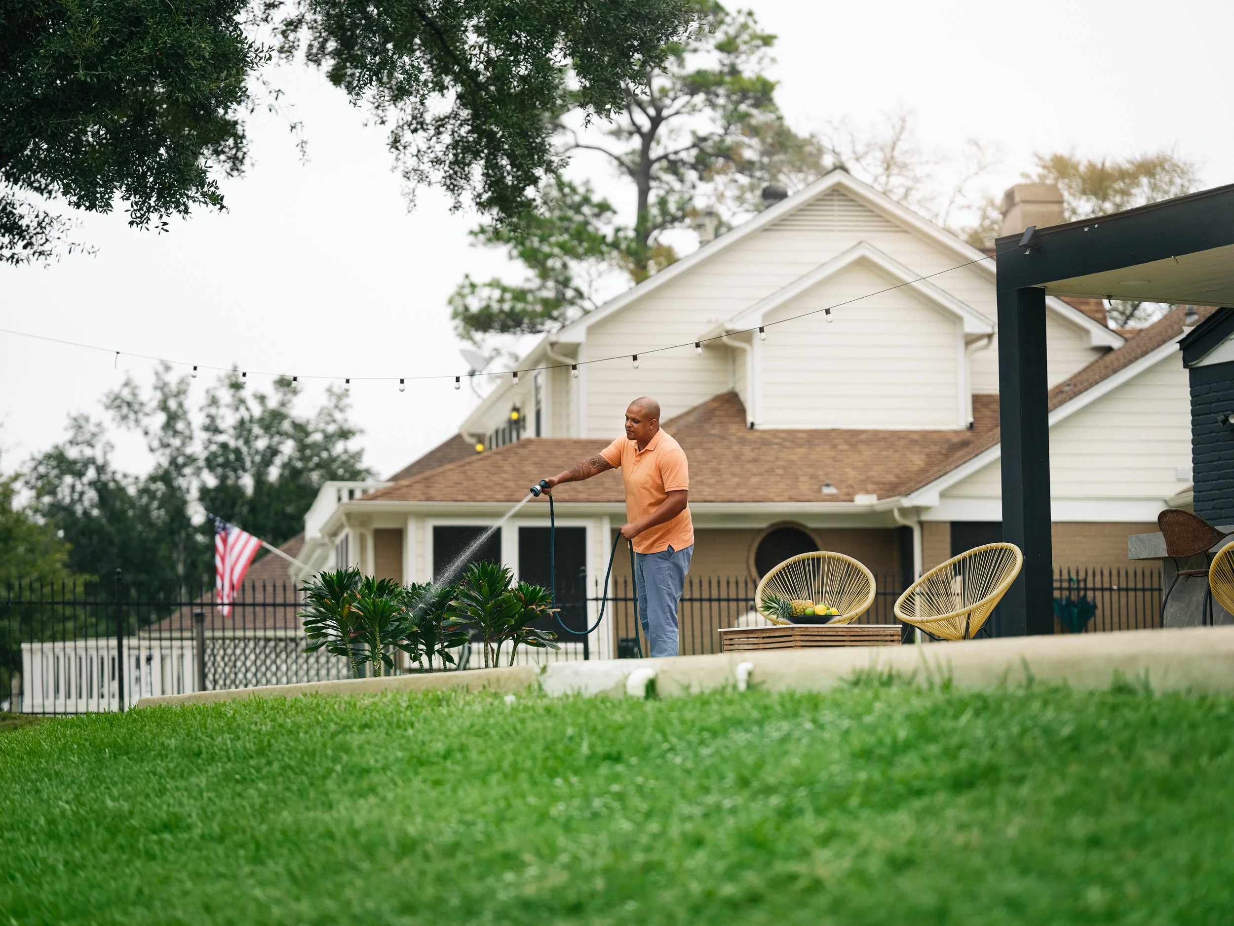 Man watering garden lawn in residential backyard
