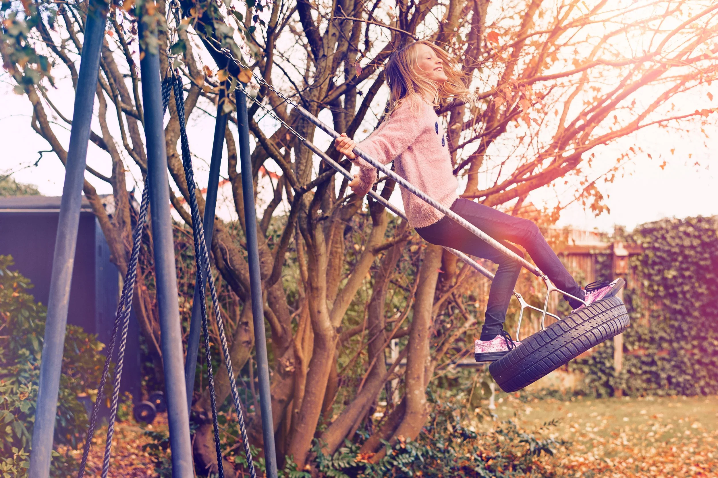 Child swinging on tire swing in garden, outdoor play in residential setting