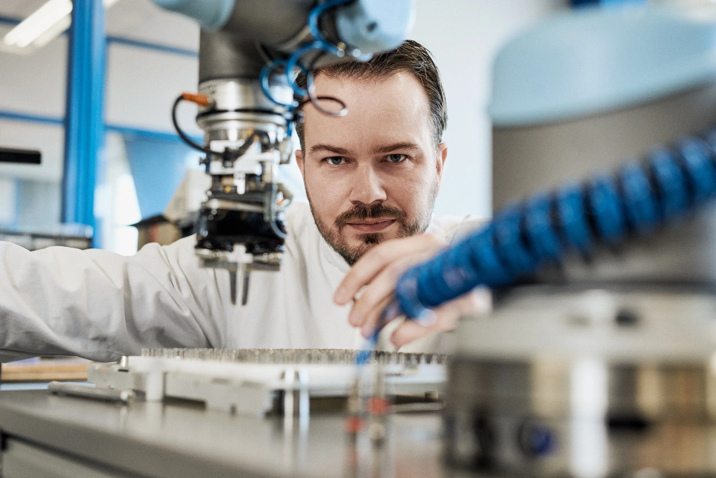 Technician working closely with robotic arm assembling components on production line