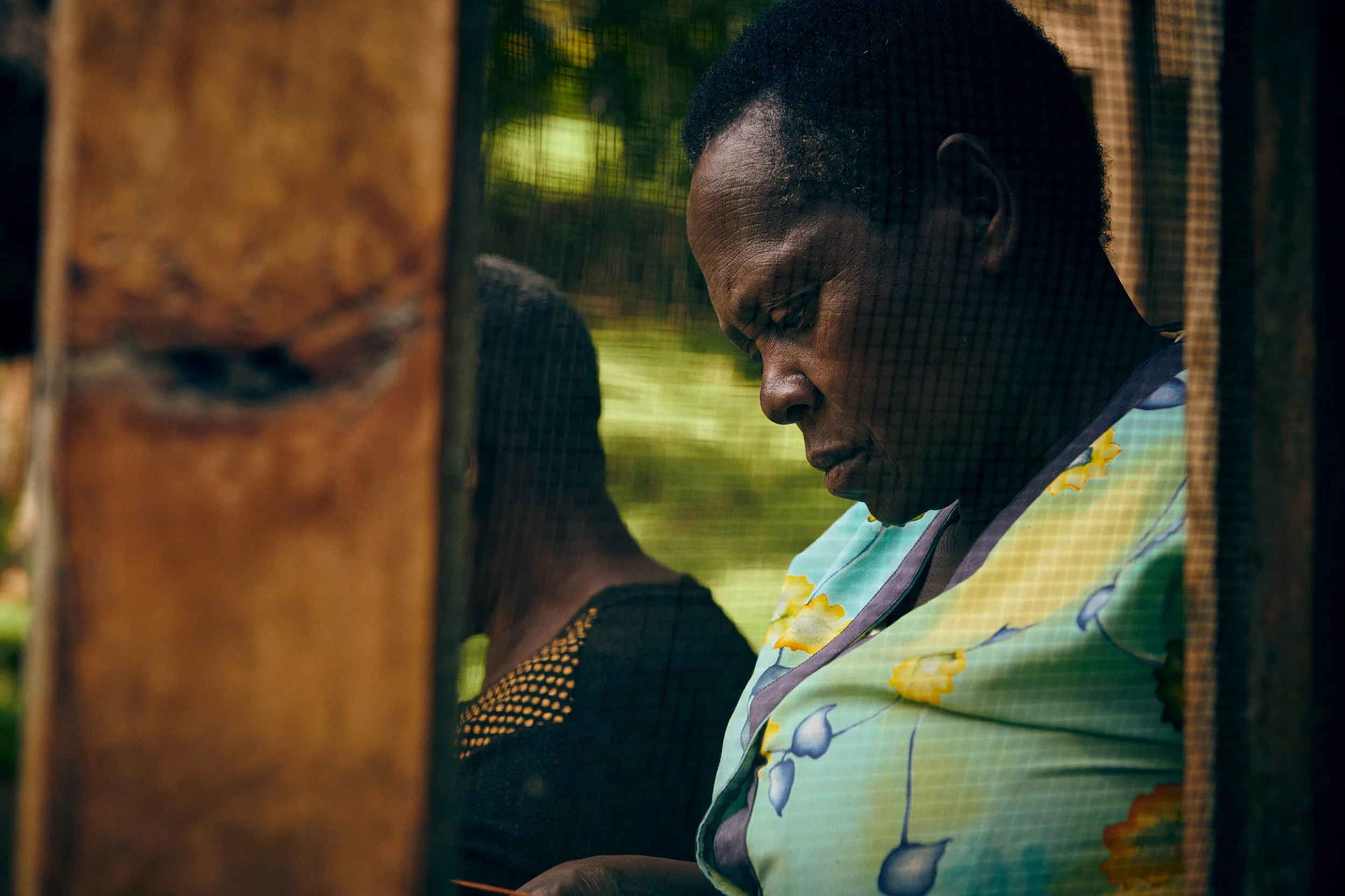 Woman seated by doorway looking down, quiet moment in domestic environment