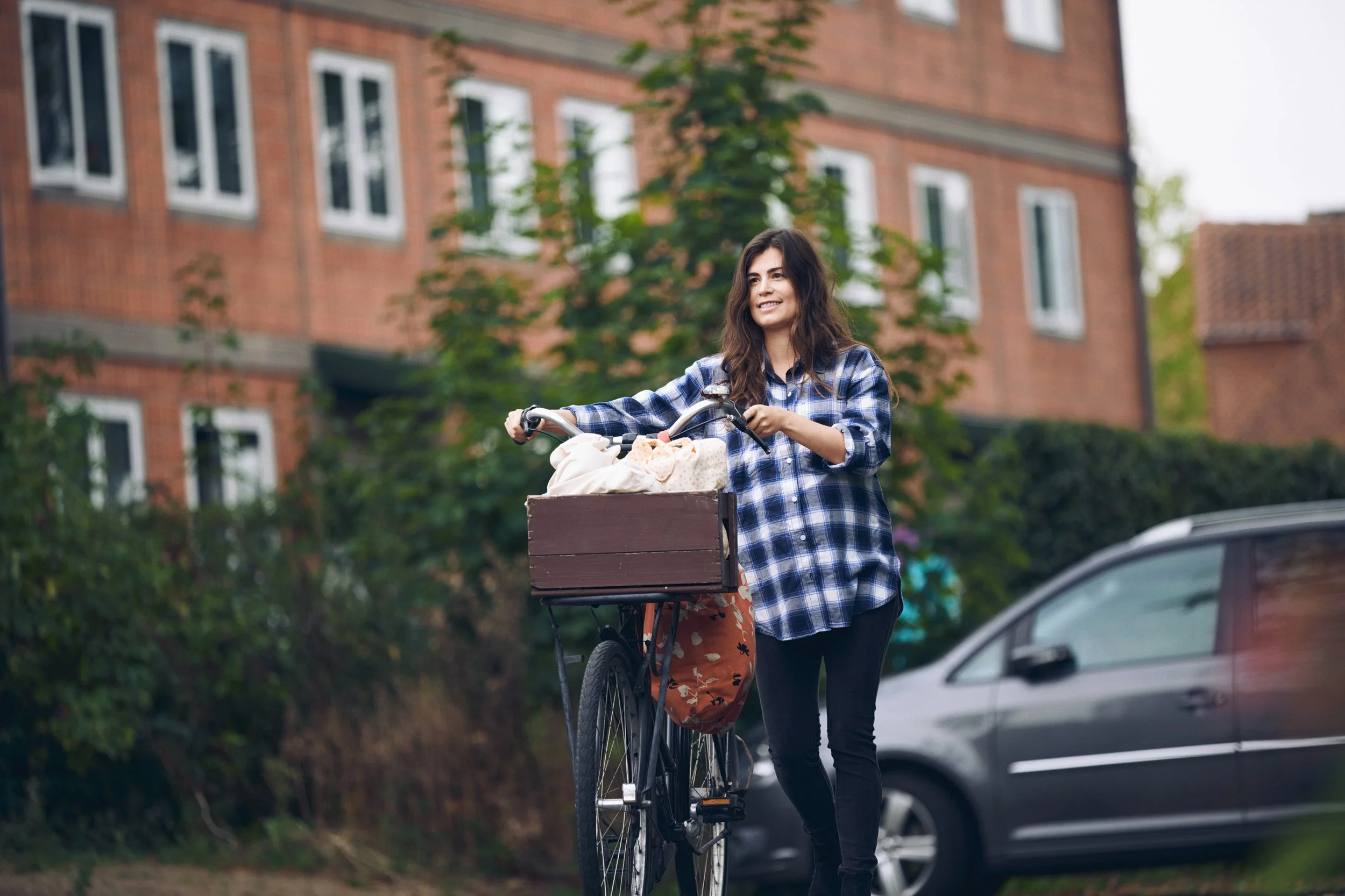 Woman walking with bicycle through residential street, everyday urban mobility