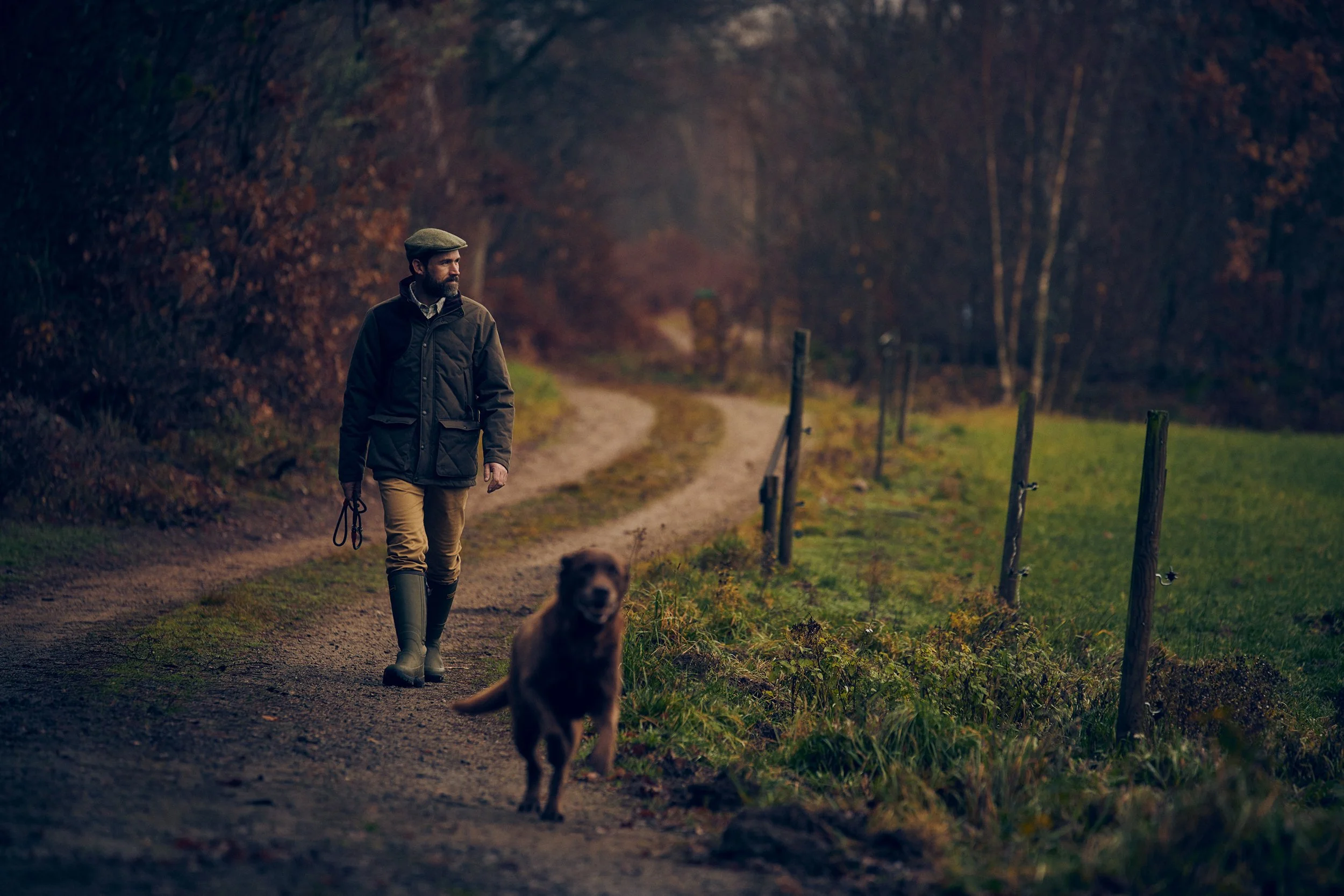 Hunter walking along rural path with dog, quiet movement through landscape