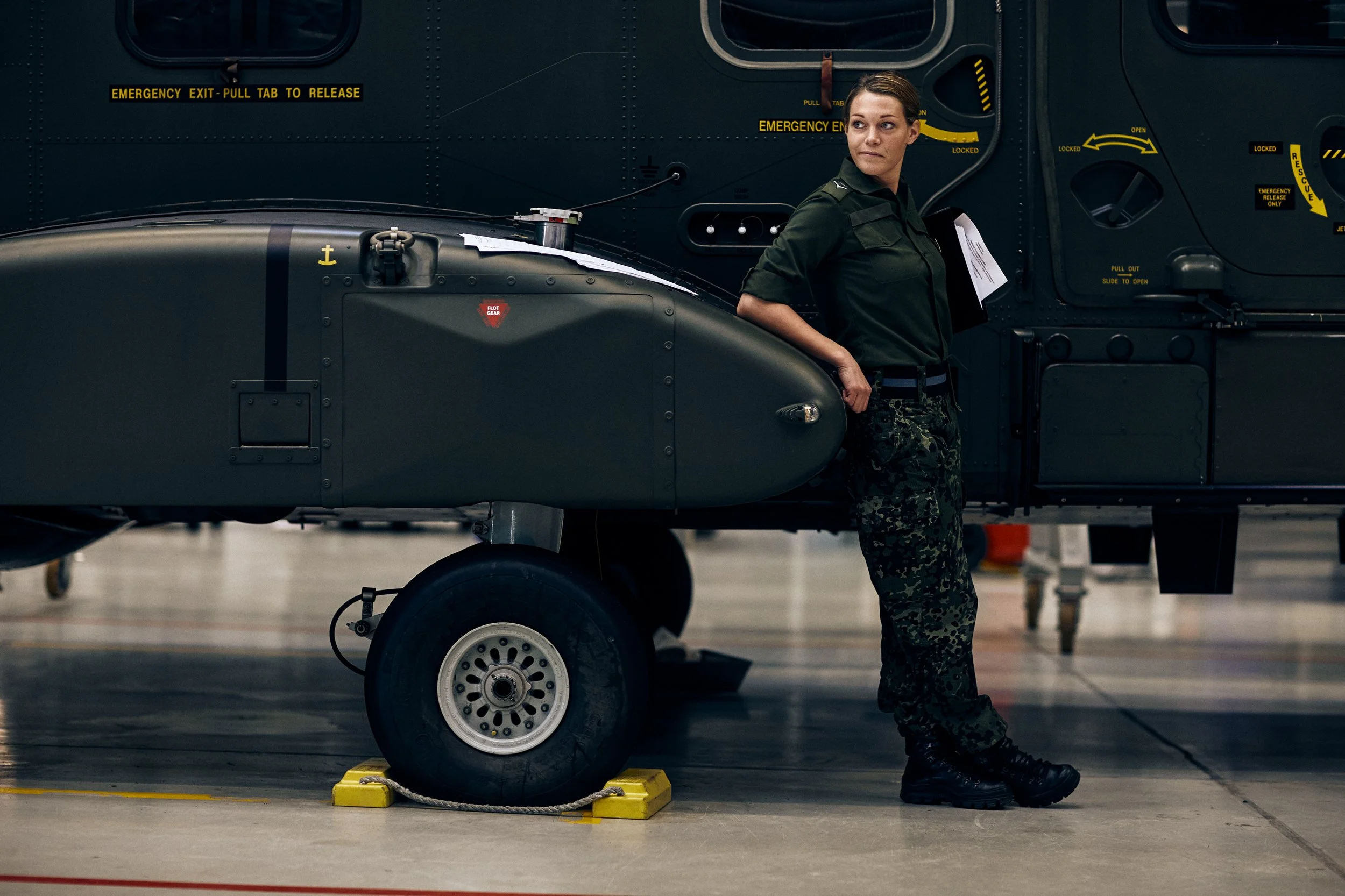 Soldier standing next to military helicopter in hangar