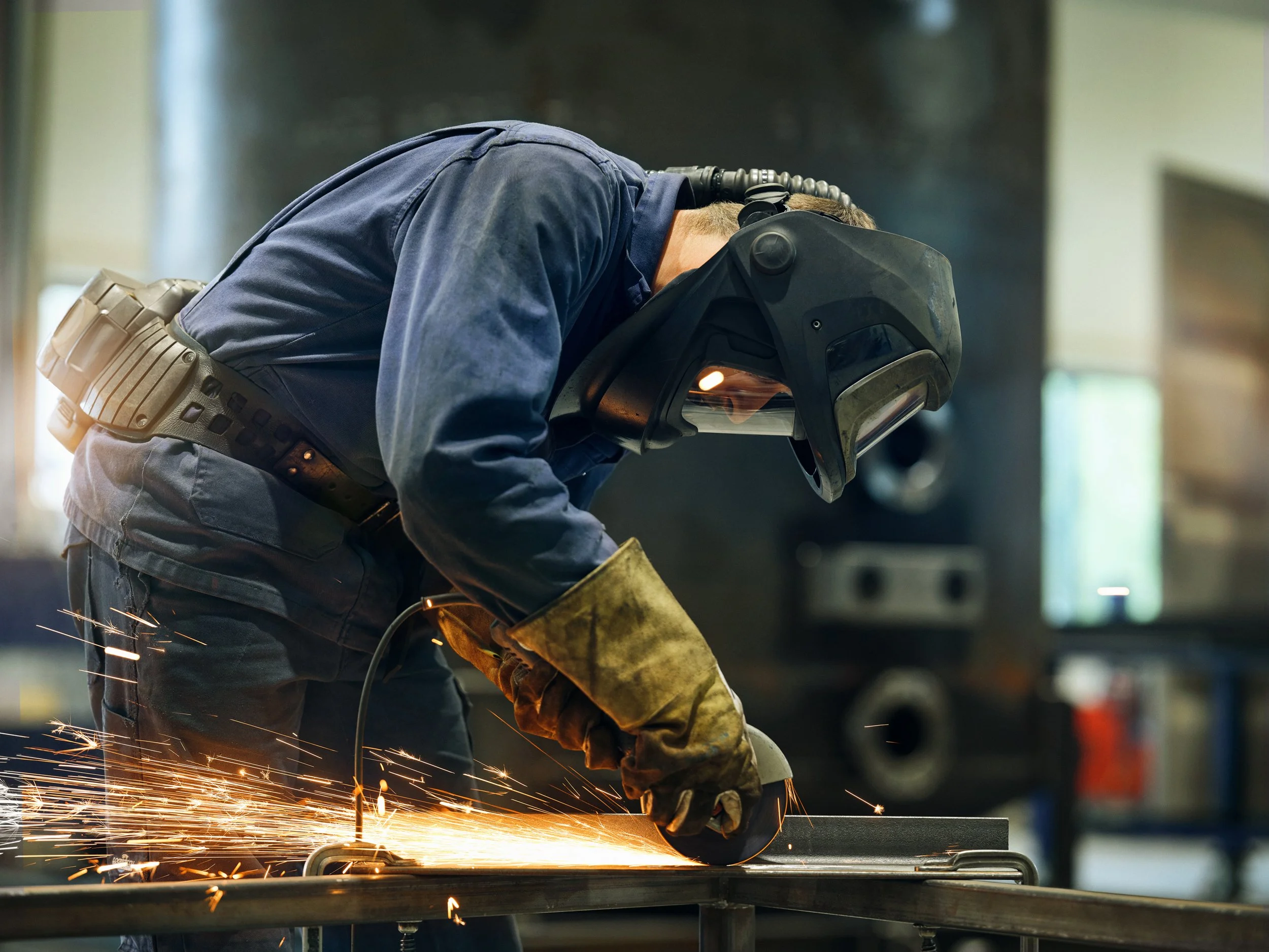 Welder grinding metal with sparks in workshop