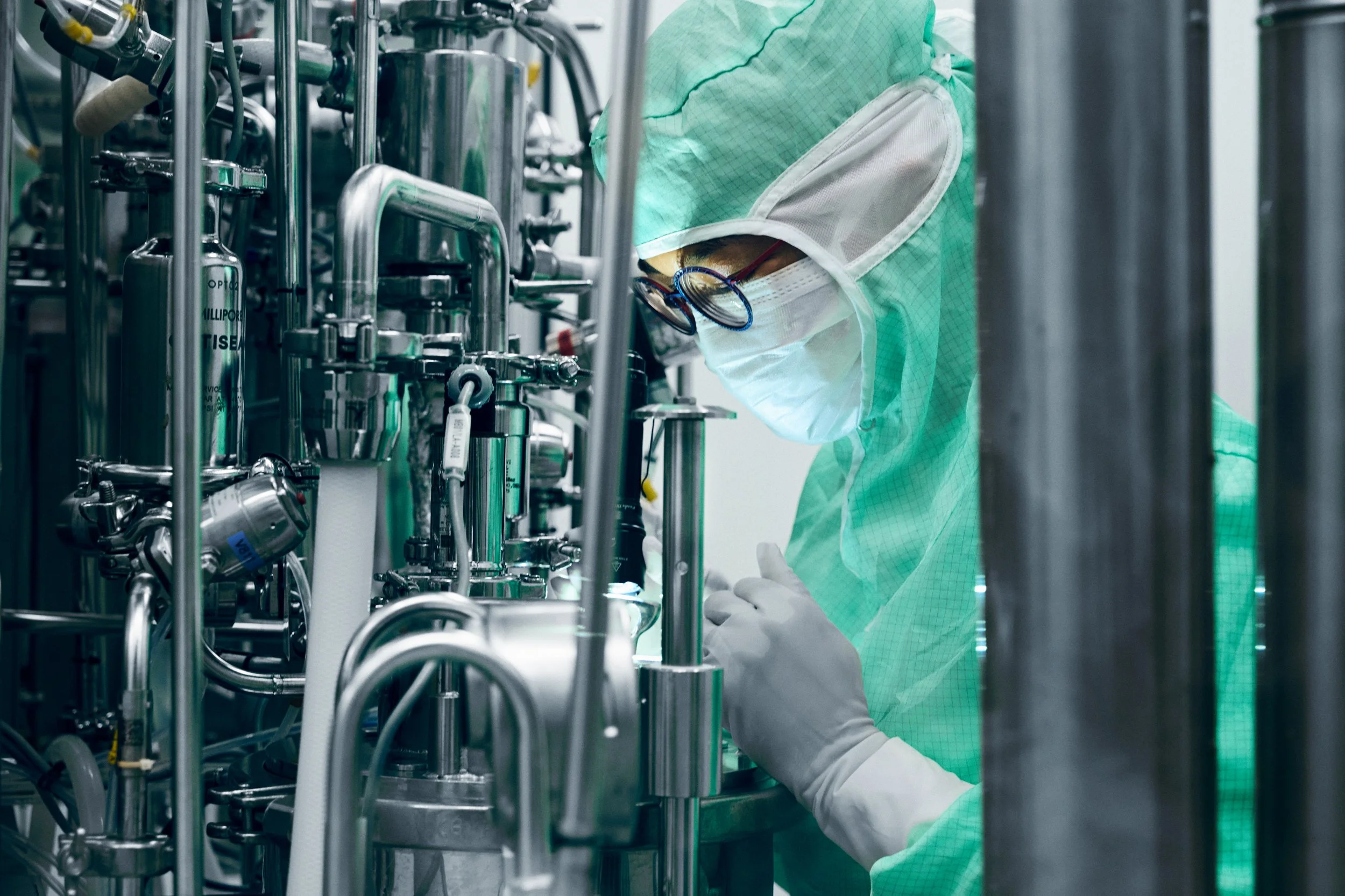 Technician operating stainless steel processing system in controlled production environment