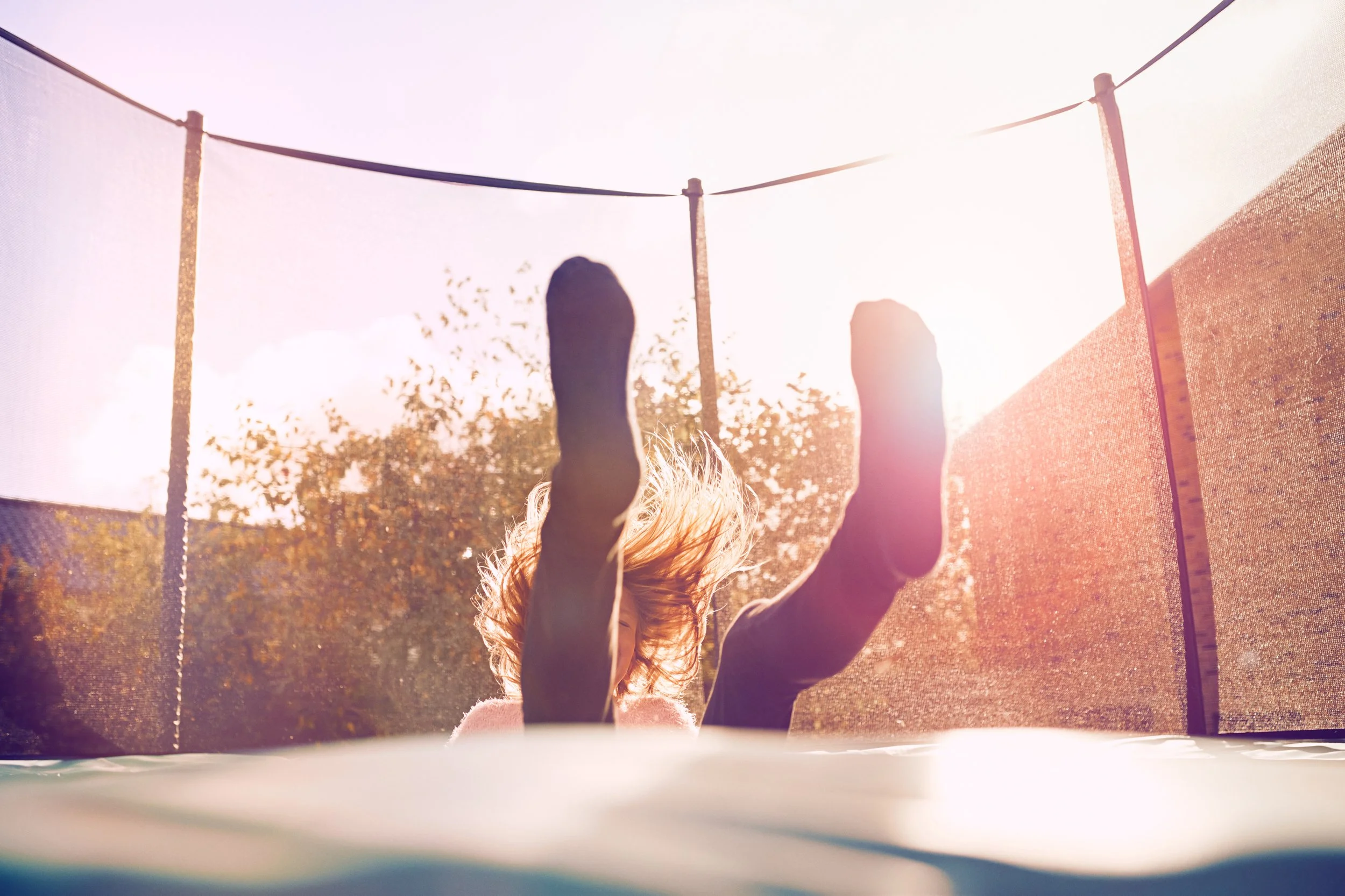 Child jumping on trampoline, movement and activity in backyard environment