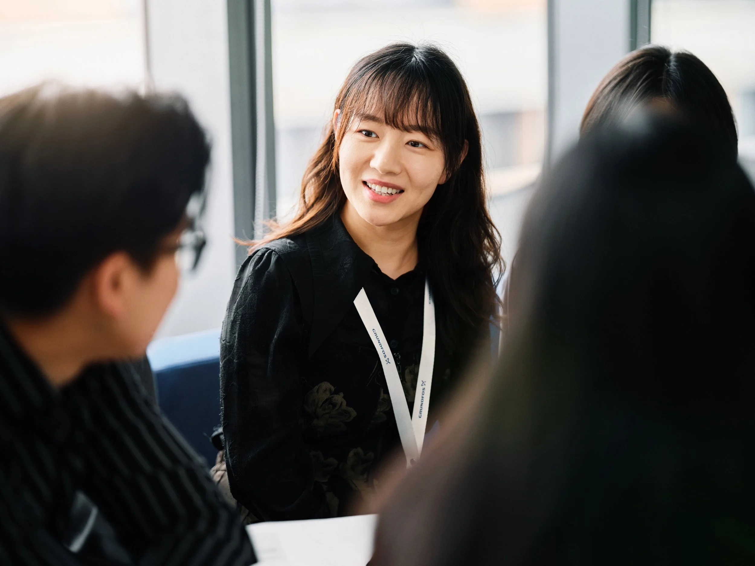 Young professional woman in meeting smiling and engaging with colleagues in bright office space