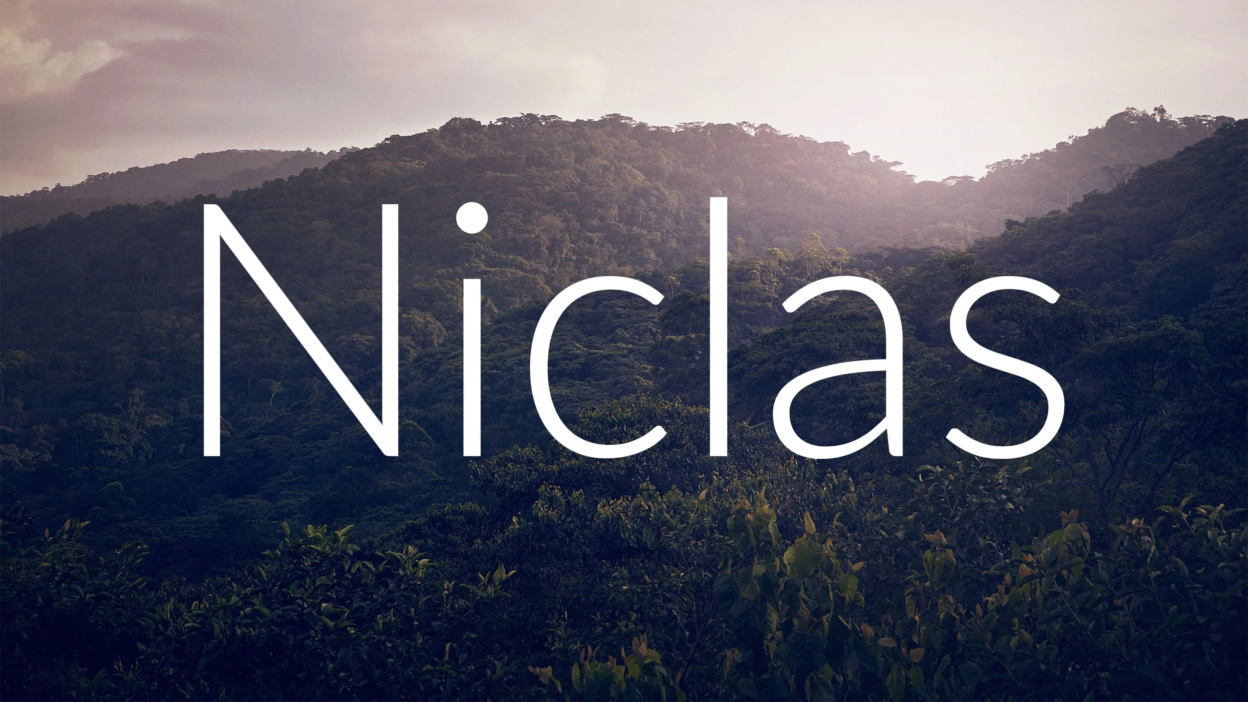 A view of a lush green forested mountain landscape with the word 'Nicias' overlayed in large white text.