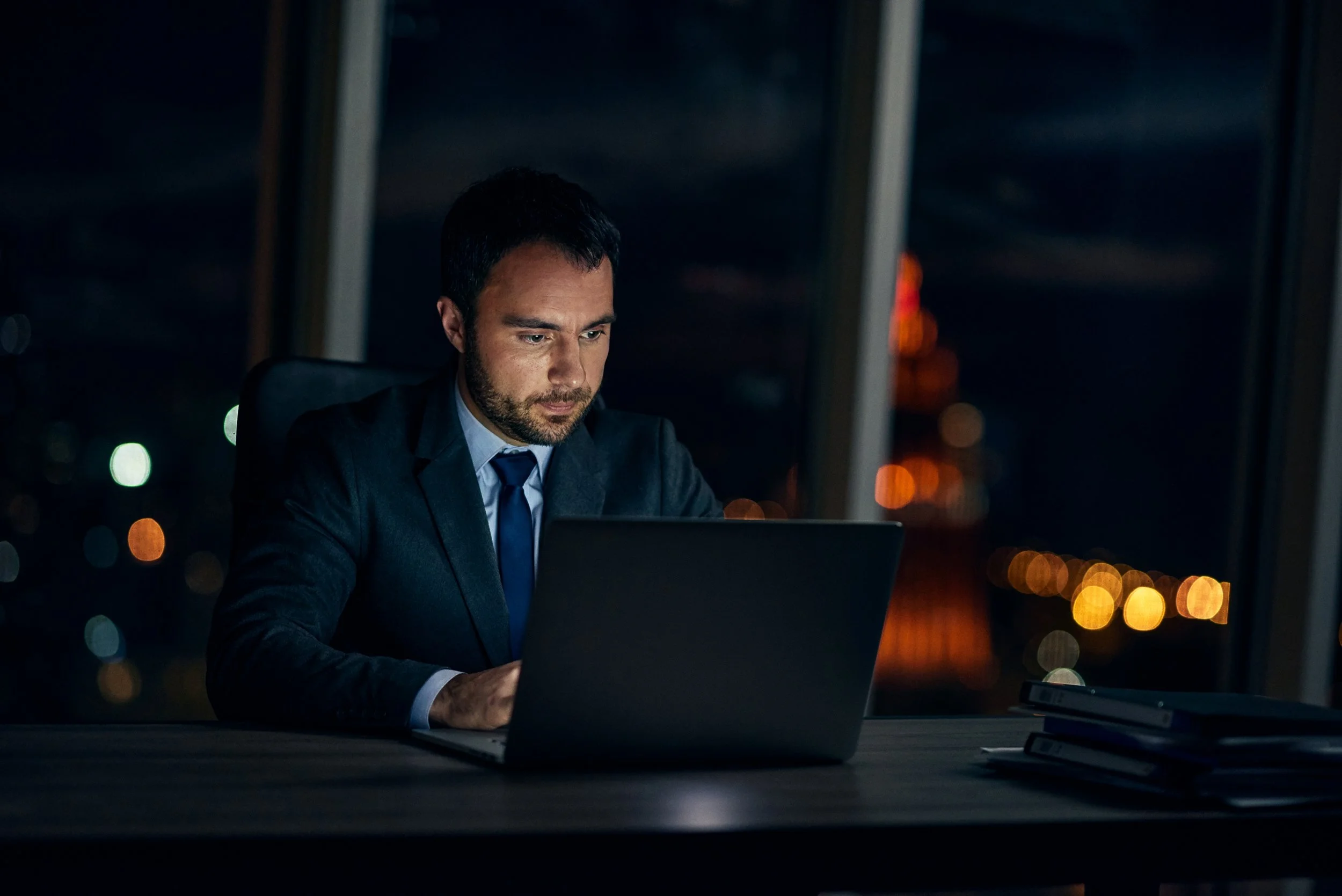 Man working on laptop at desk at night, focused work situation