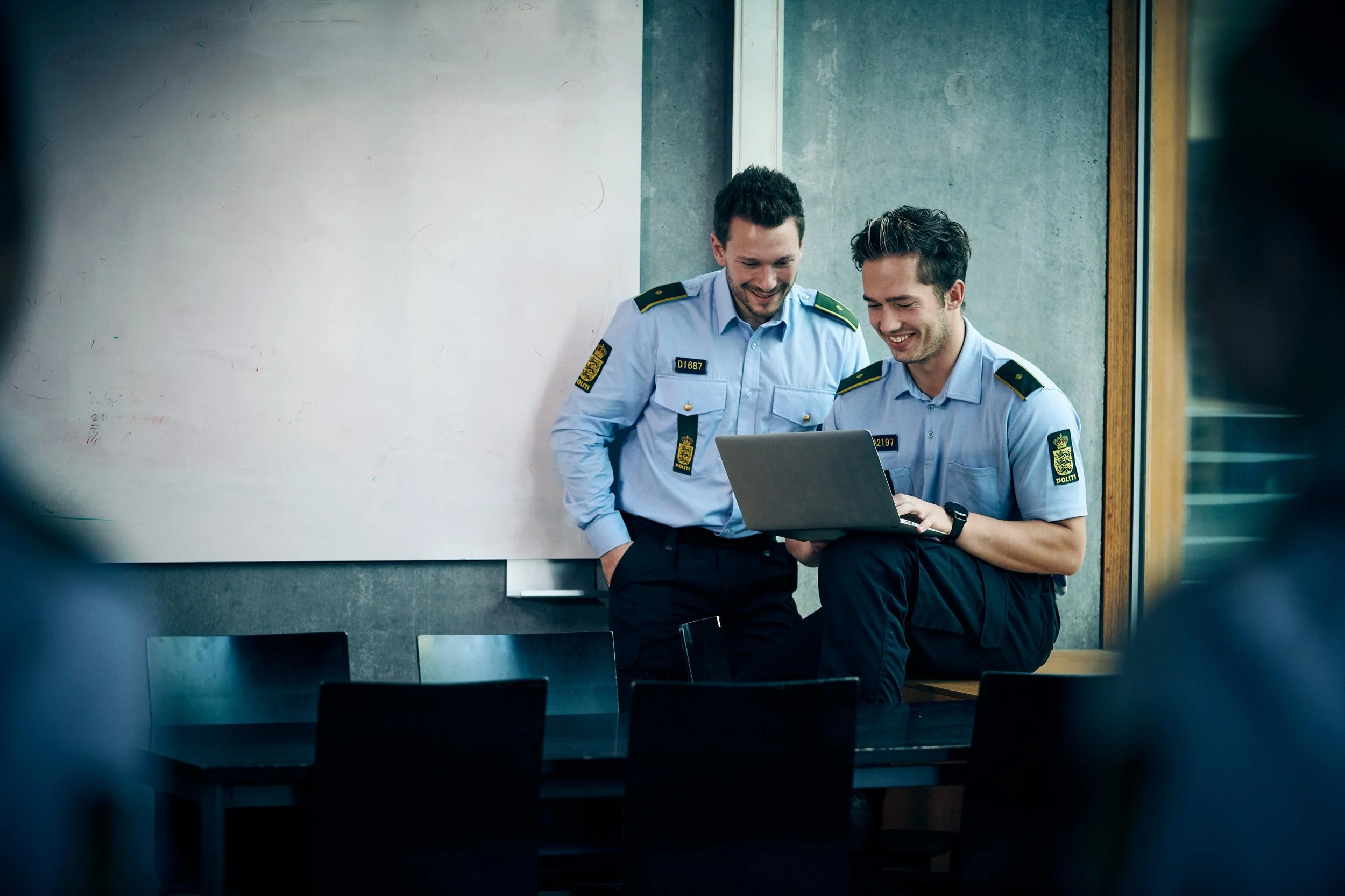 Two police officers reviewing content on laptop indoors