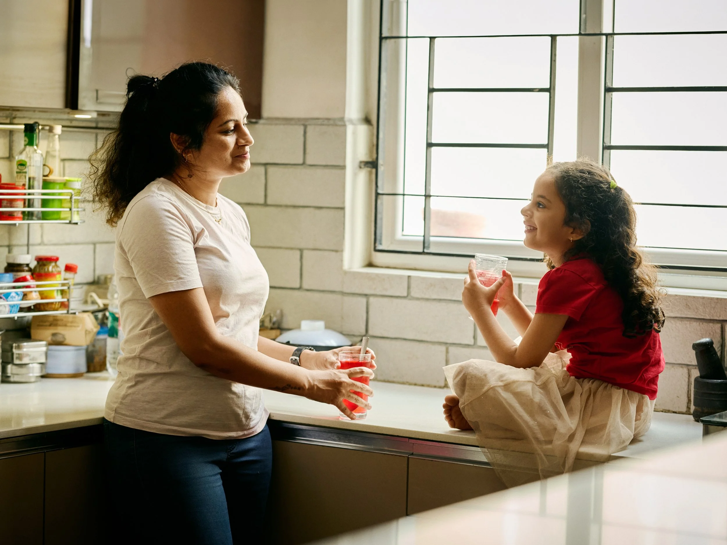Mother and child drinking water together in kitchen
