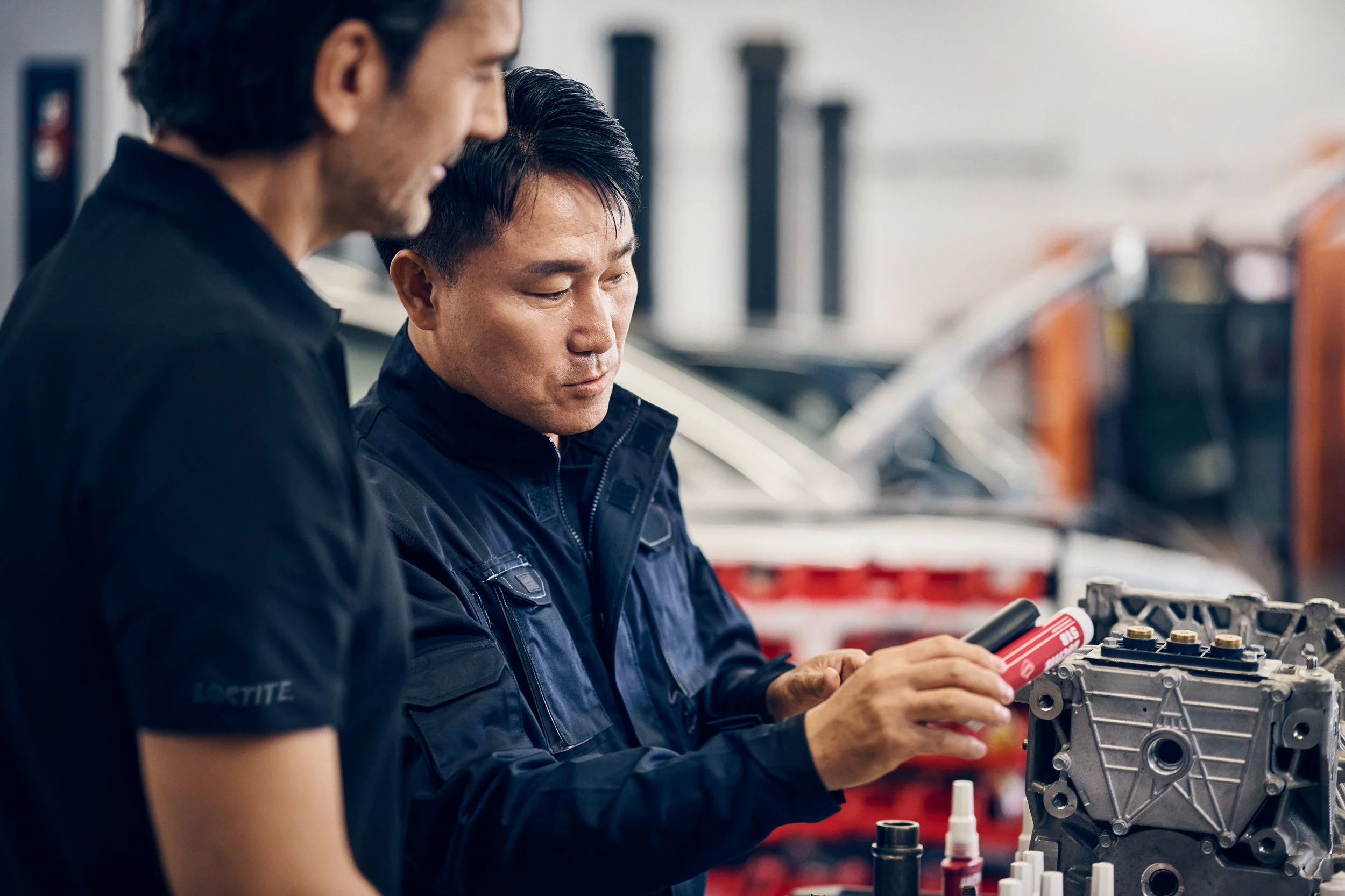 Two technicians examining component together, hands-on collaboration in workshop