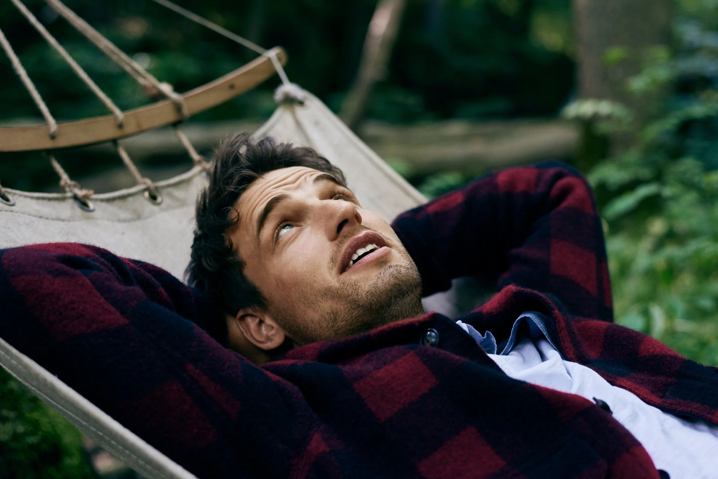 Man lying in hammock in forest, relaxed outdoor moment