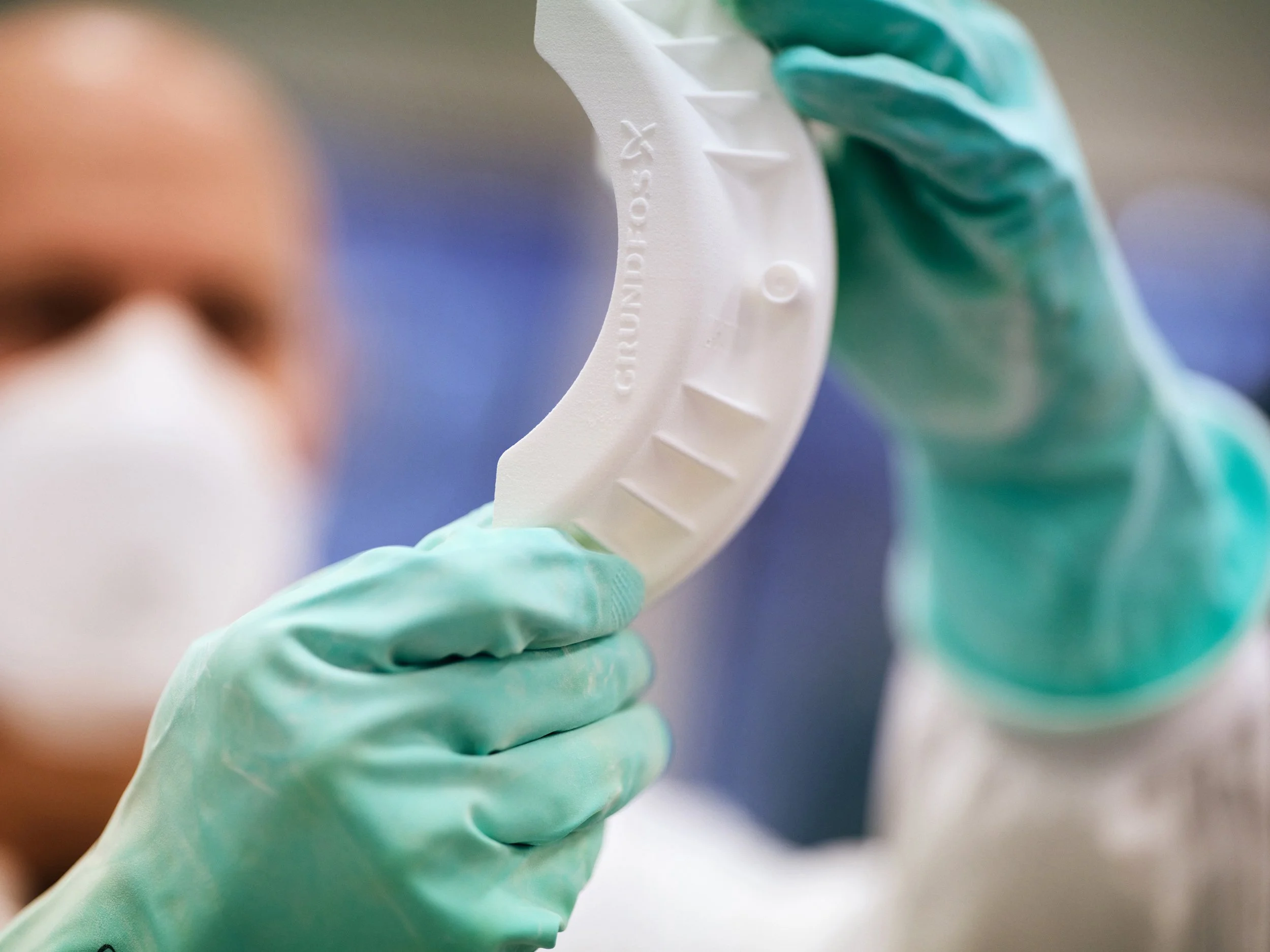 Technician inspecting white prototype component in lab, focus on material and form