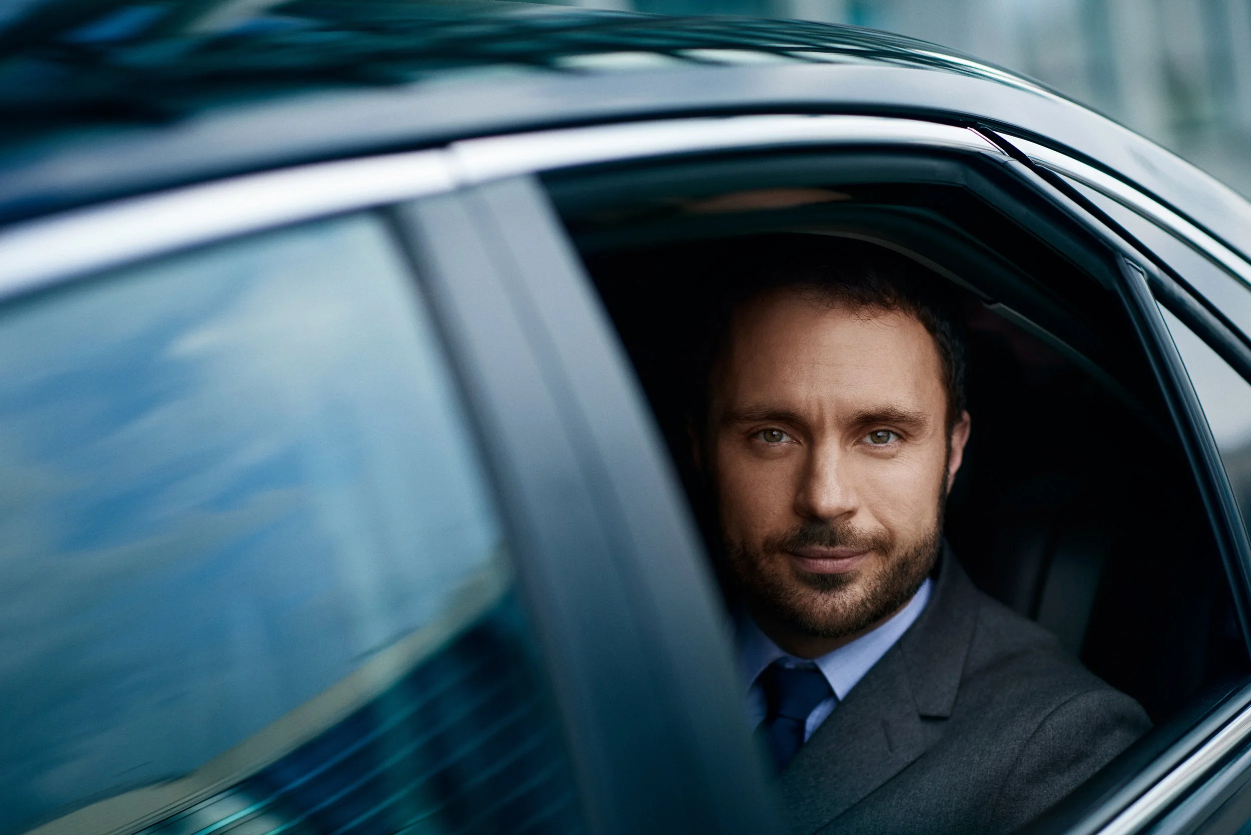 Man seated in car looking out of window, urban mobility moment