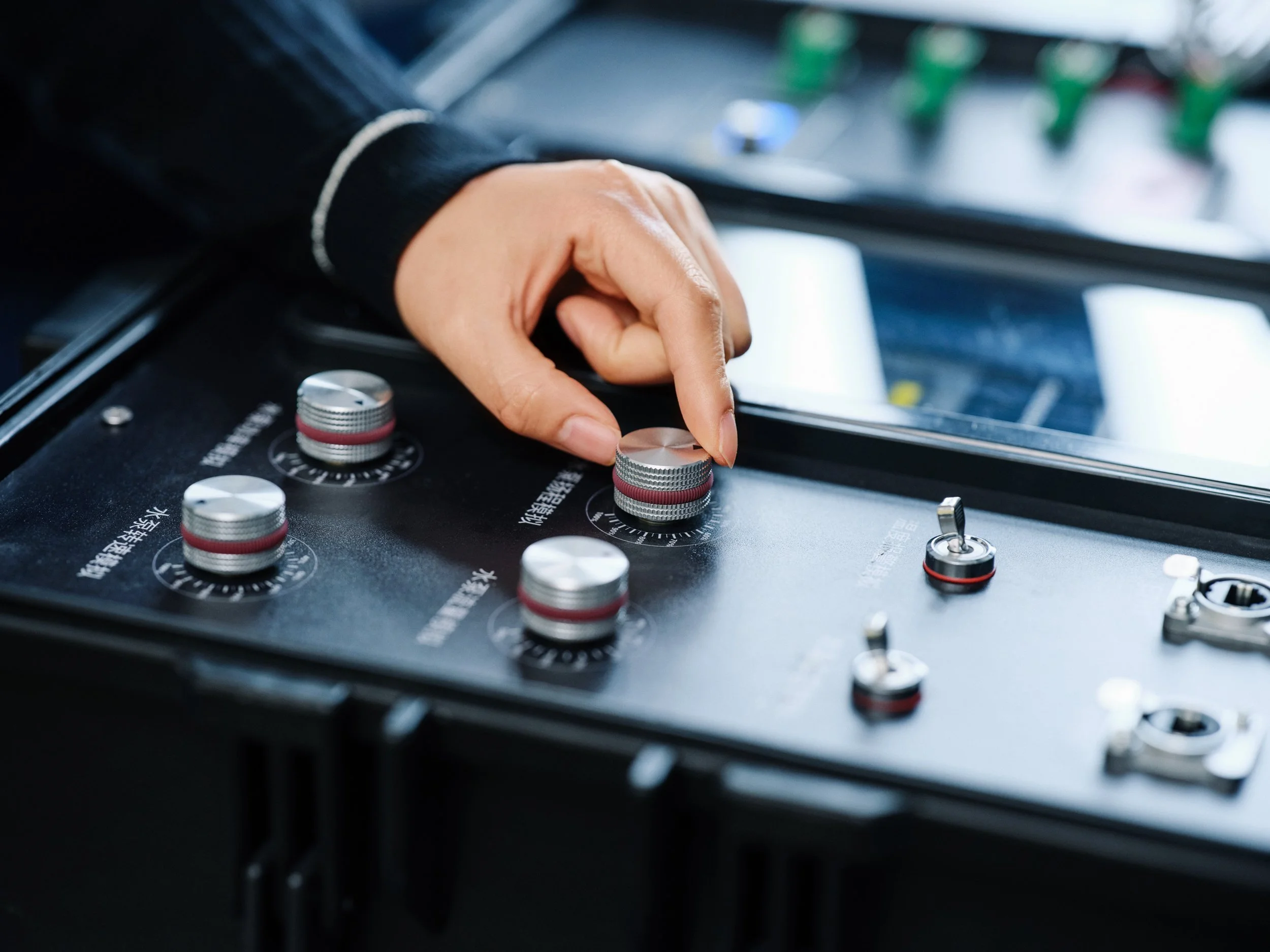 Hand adjusting control dials on testing equipment, fine-tuning system parameters