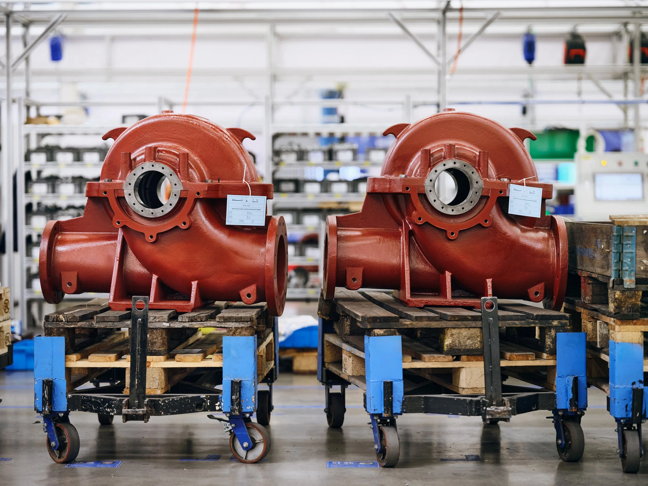Two large red pump housings placed on pallets in factory, front-facing industrial product view