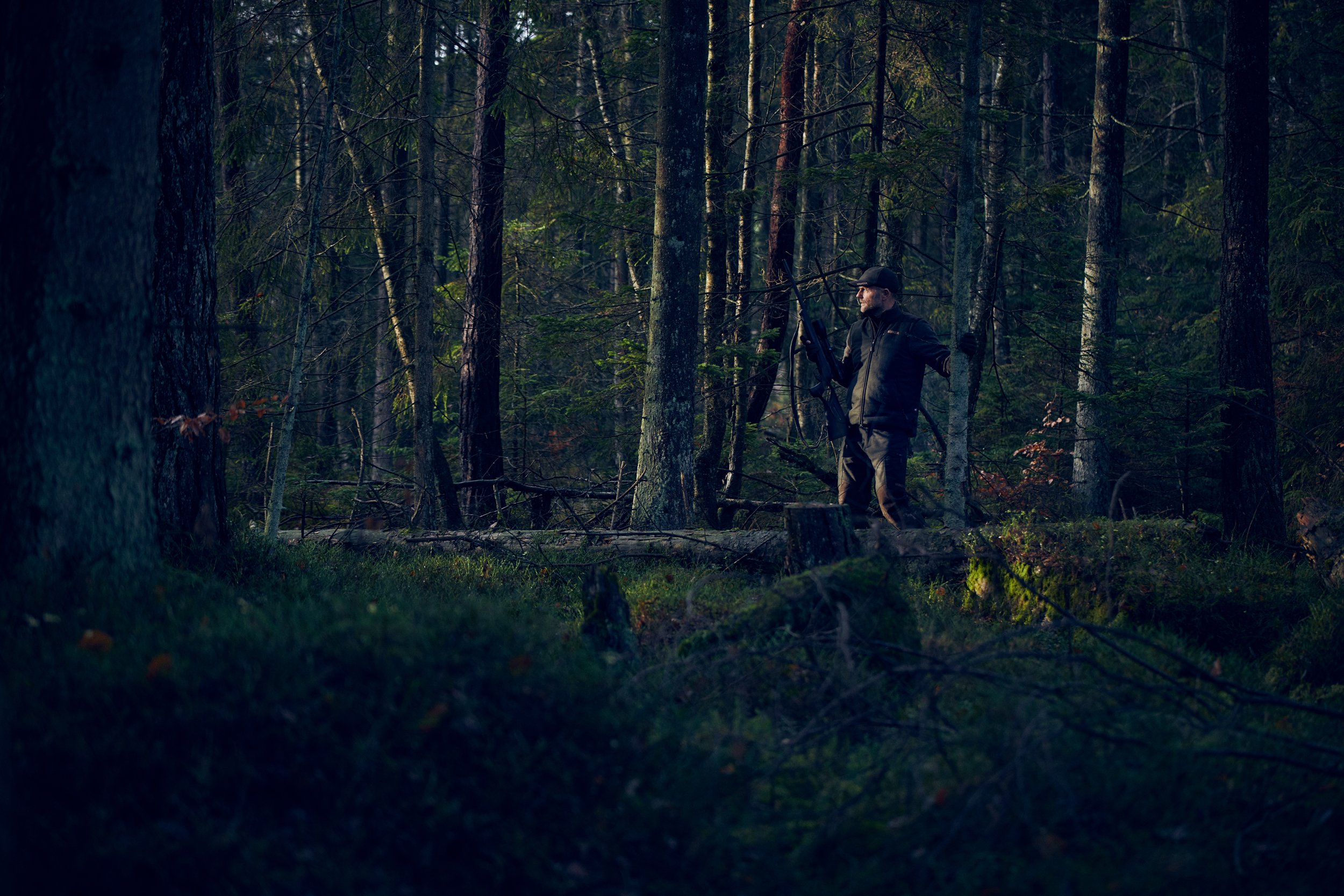 Hunter moving through forest at dusk, low light and dense surroundings