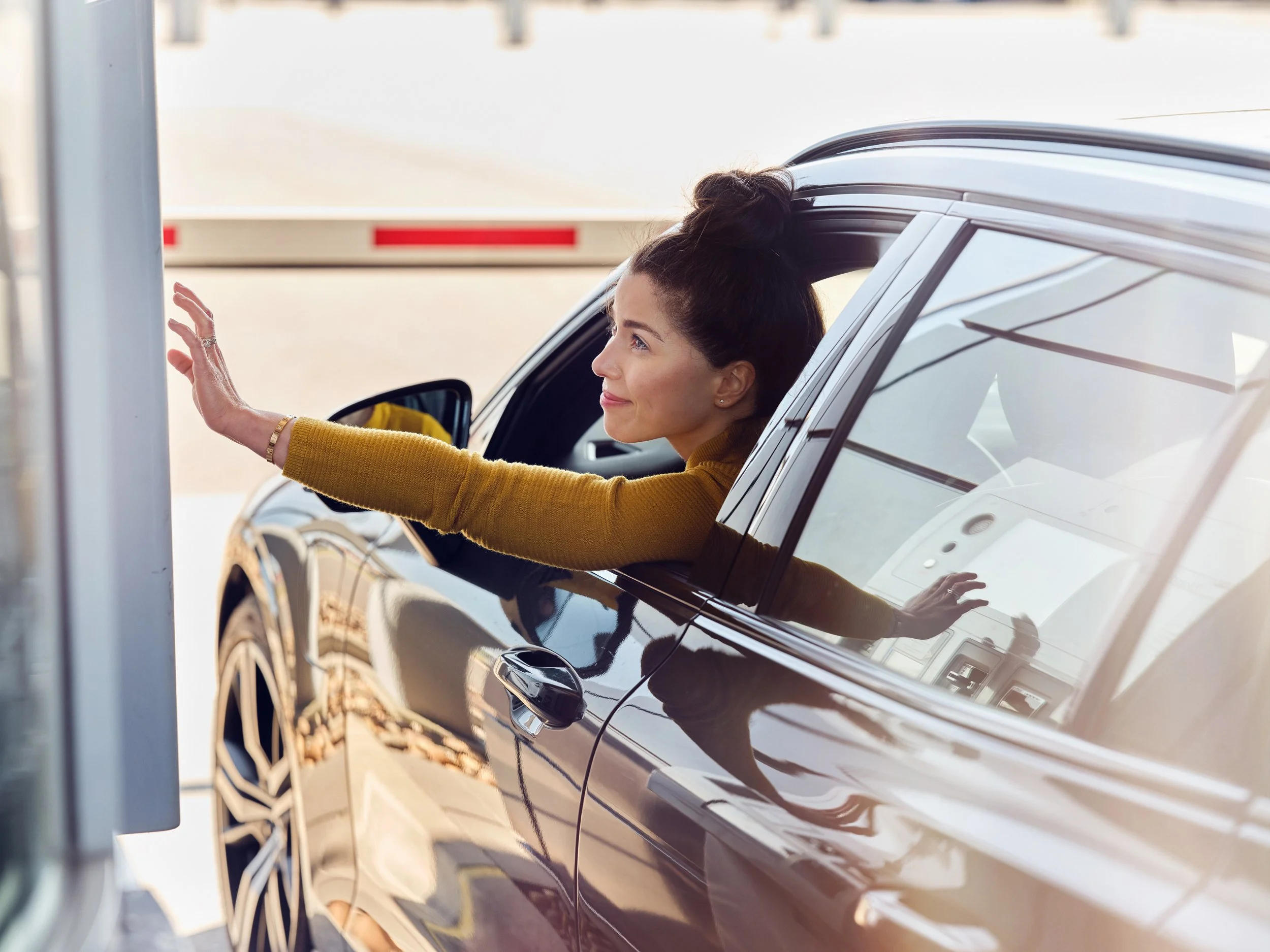 Woman in car reaching out at ferry terminal, transition between driving and boarding