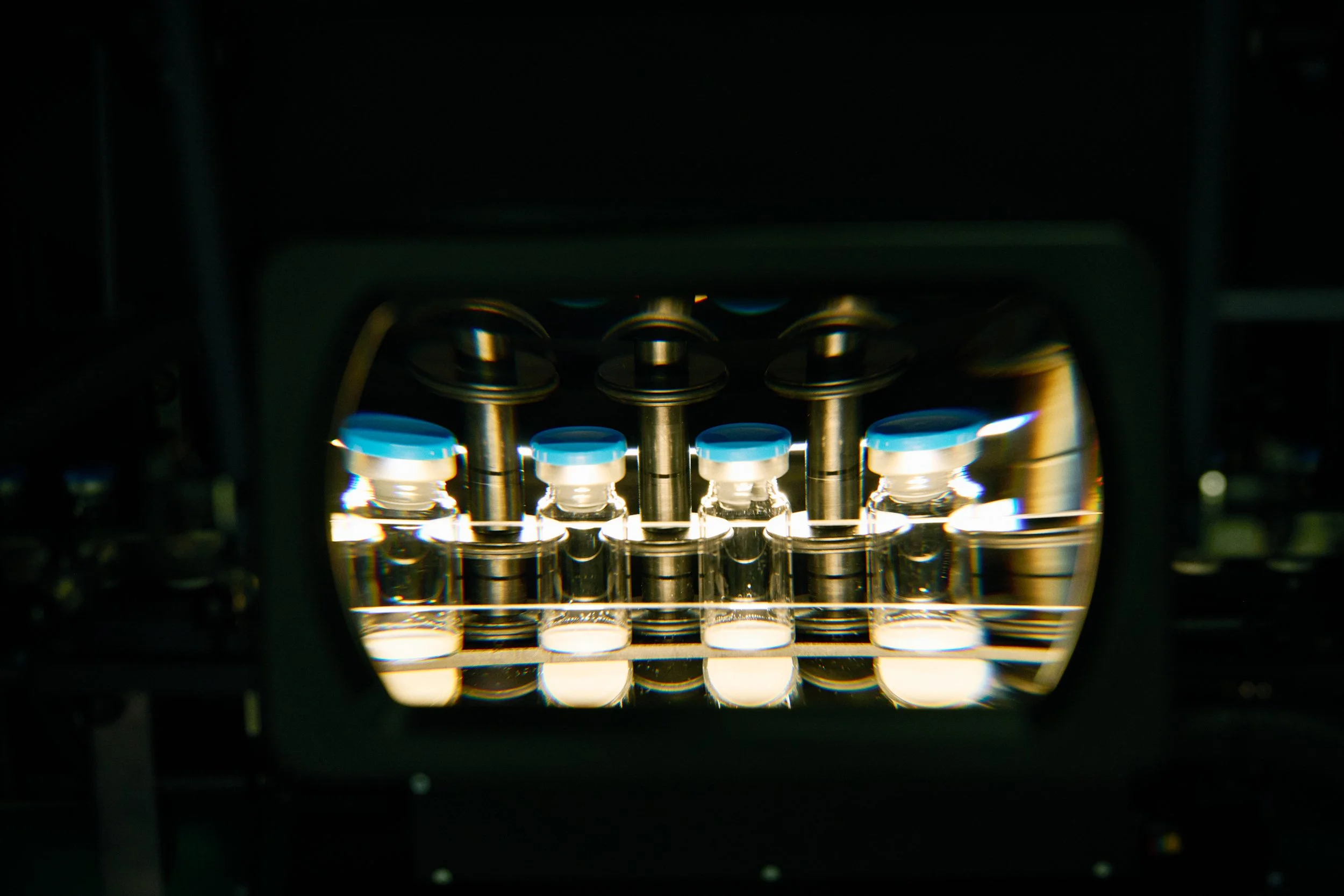 Vials positioned in automated testing or filling system under controlled lighting