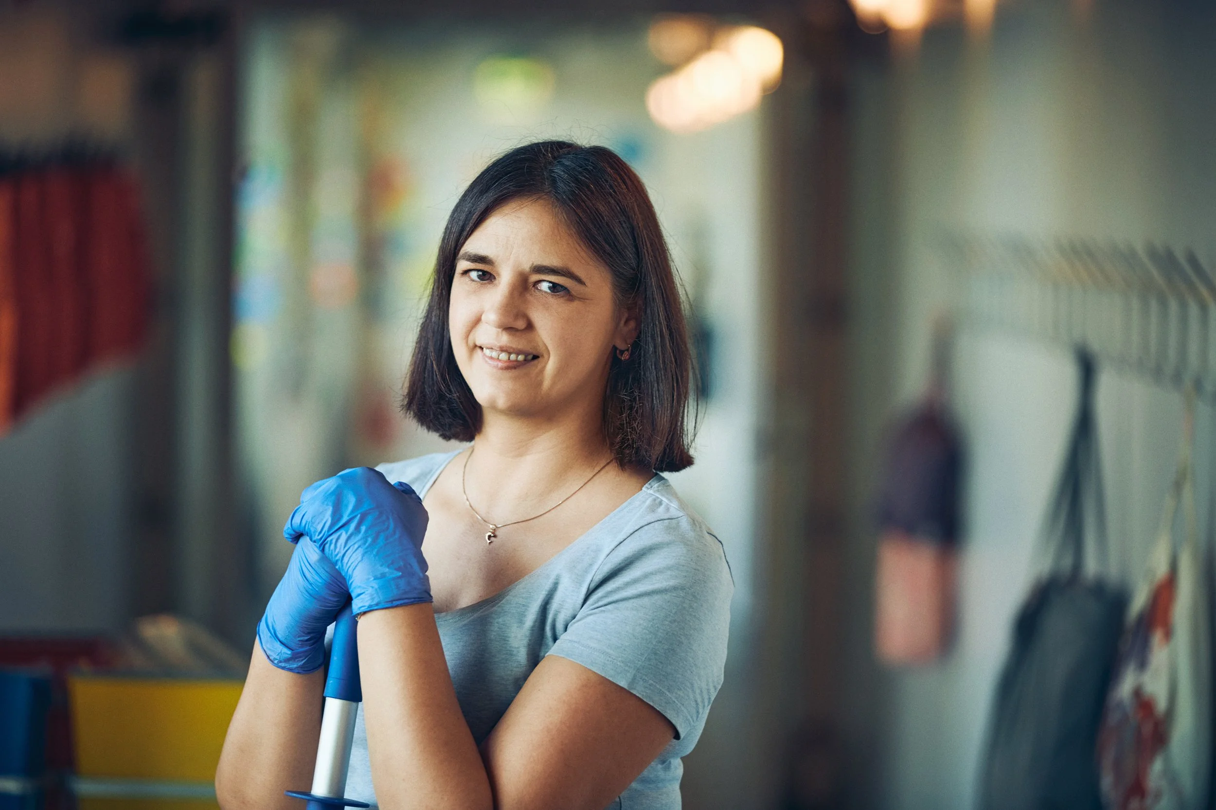 Cleaner holding mop in corridor, portrait in workplace environment