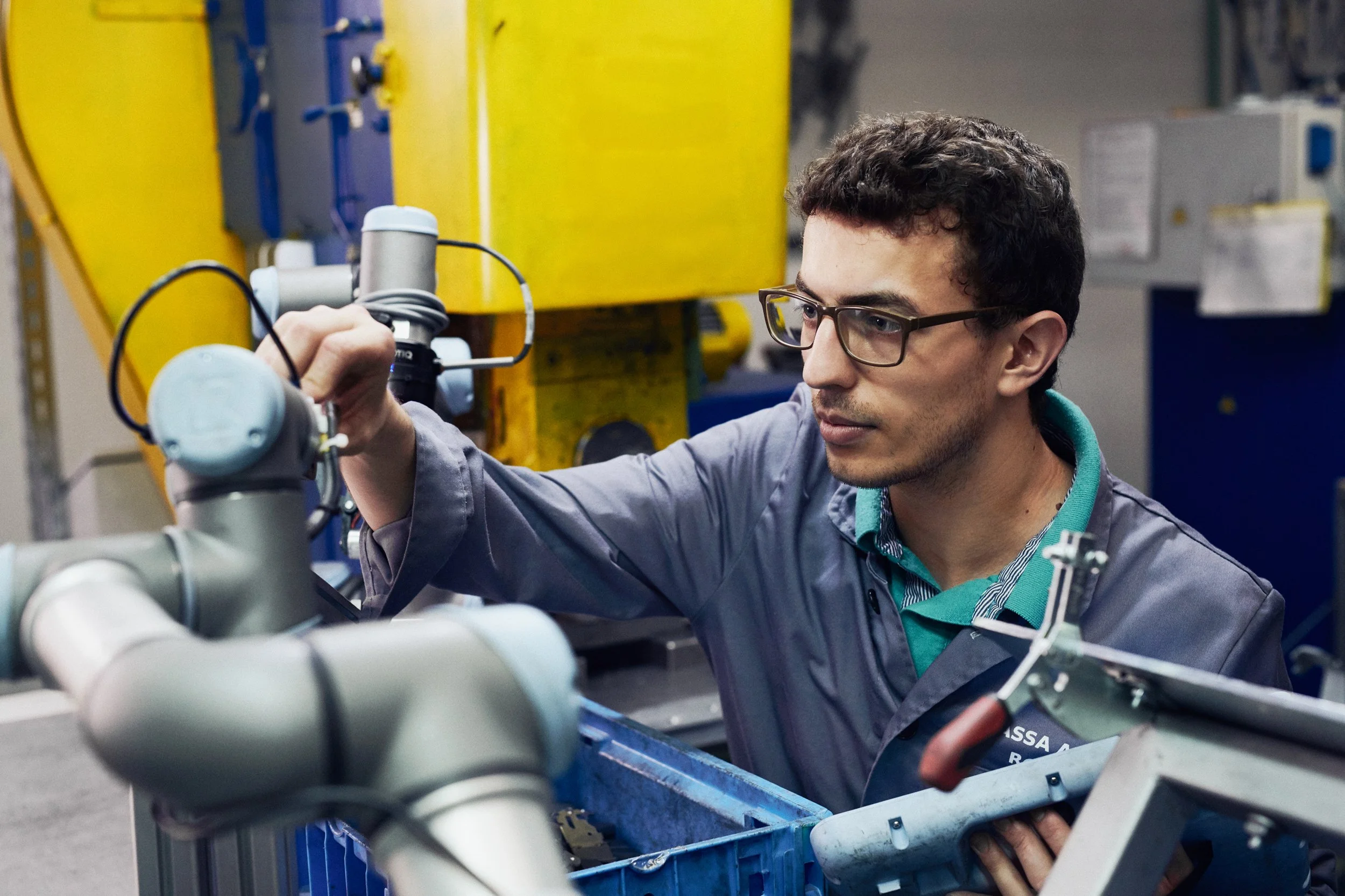 Engineer adjusting collaborative robot arm inside industrial production environment