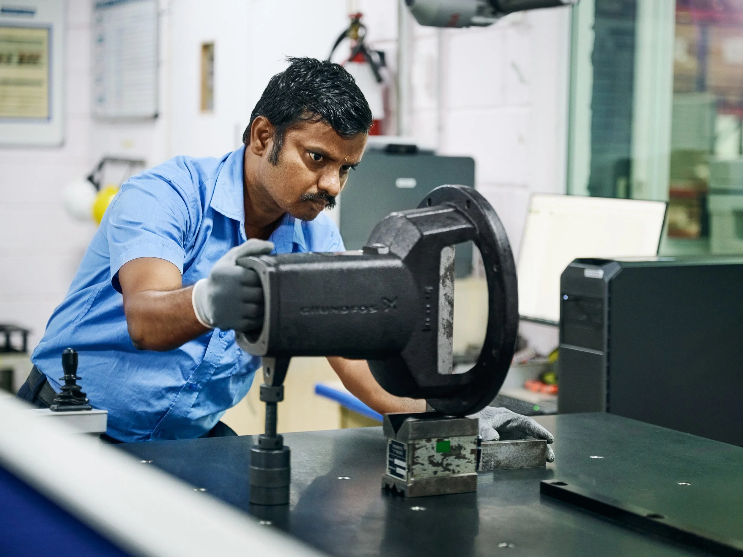 Technician positioning pump housing under measurement setup for precision testing