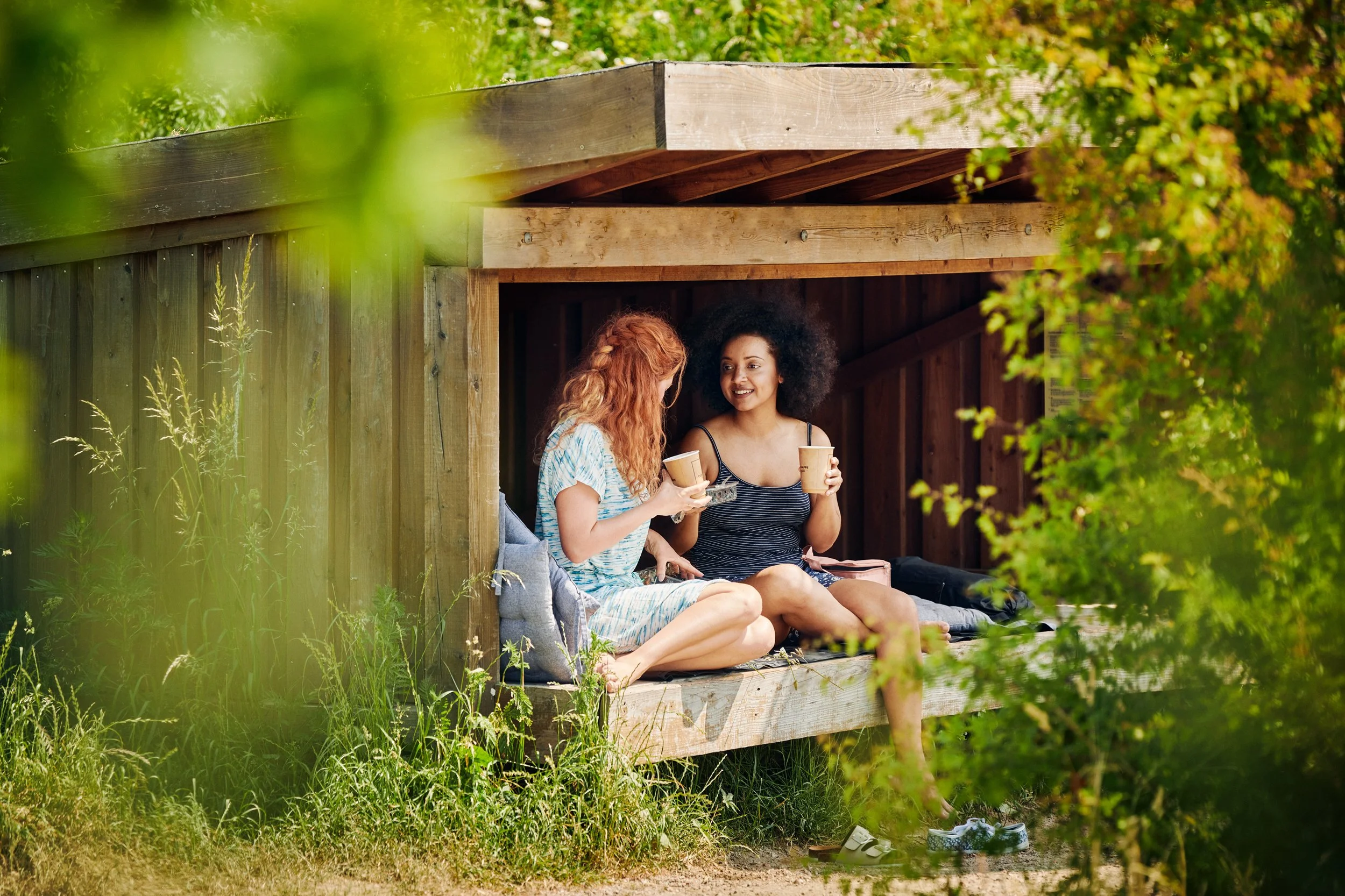 Women sitting outdoors in shelter drinking coffee, summer moment