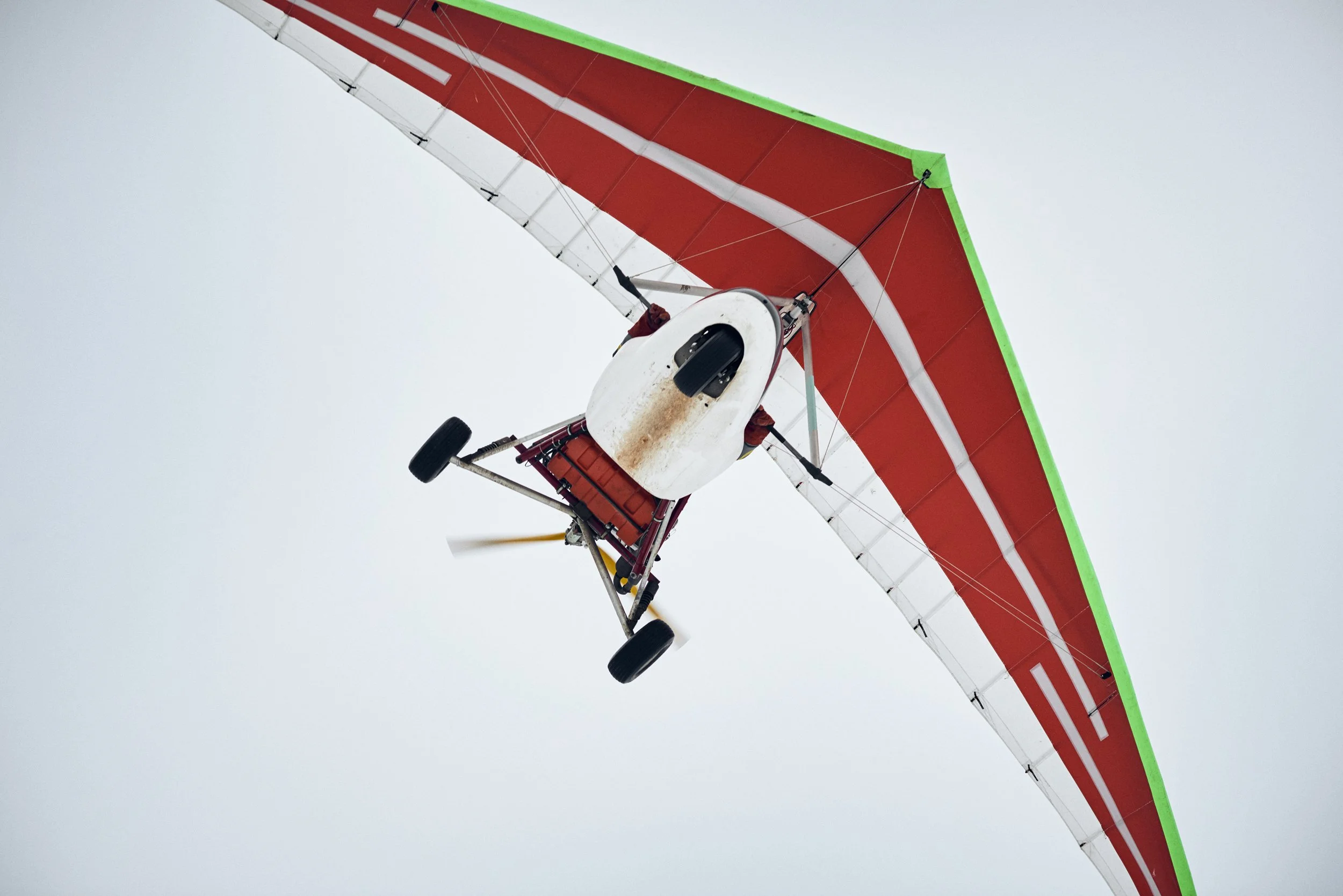 Ultralight aircraft flying overhead, minimal sky background