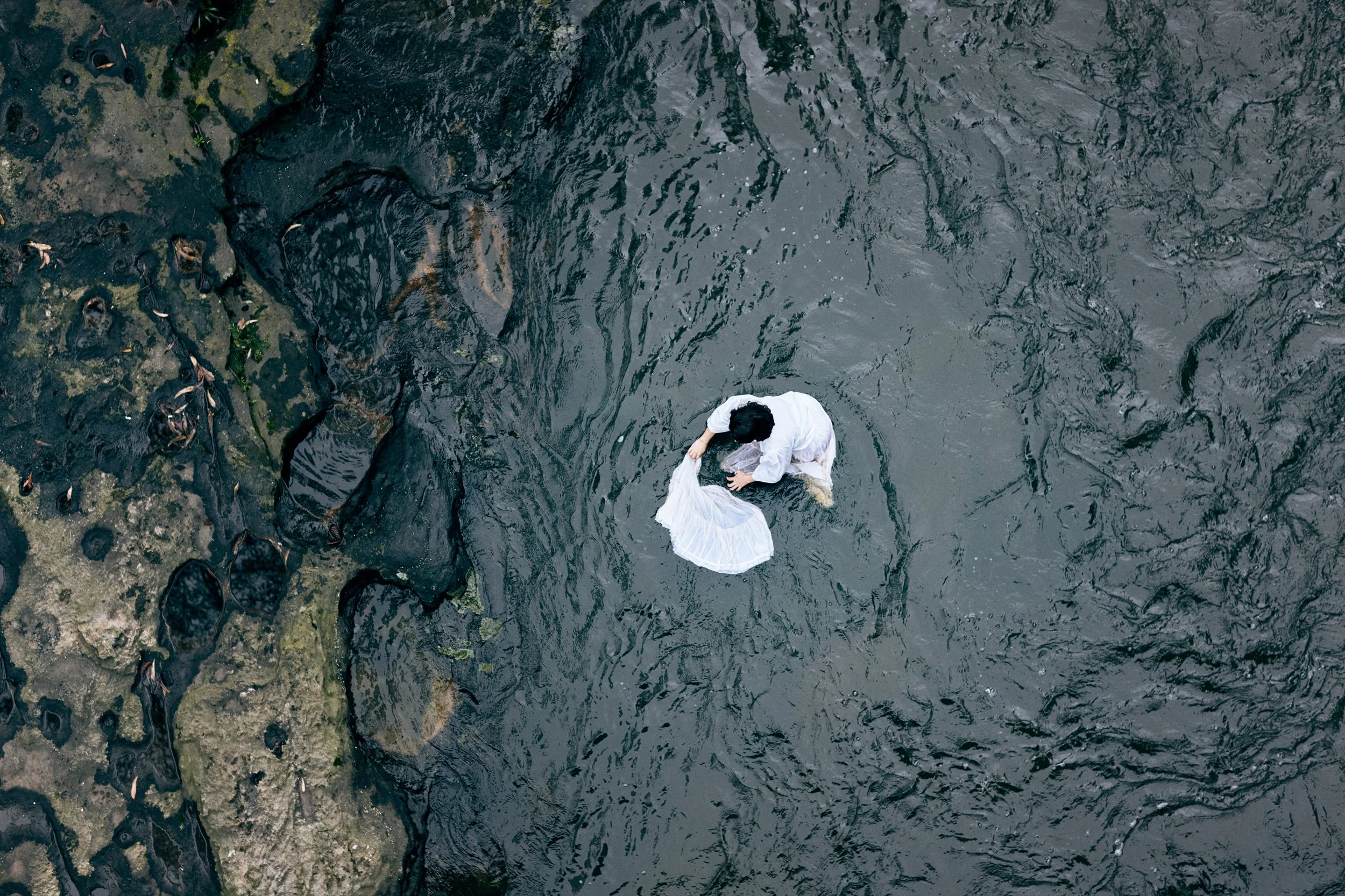 Person standing in water seen from above, illustrating environmental systems and water impact