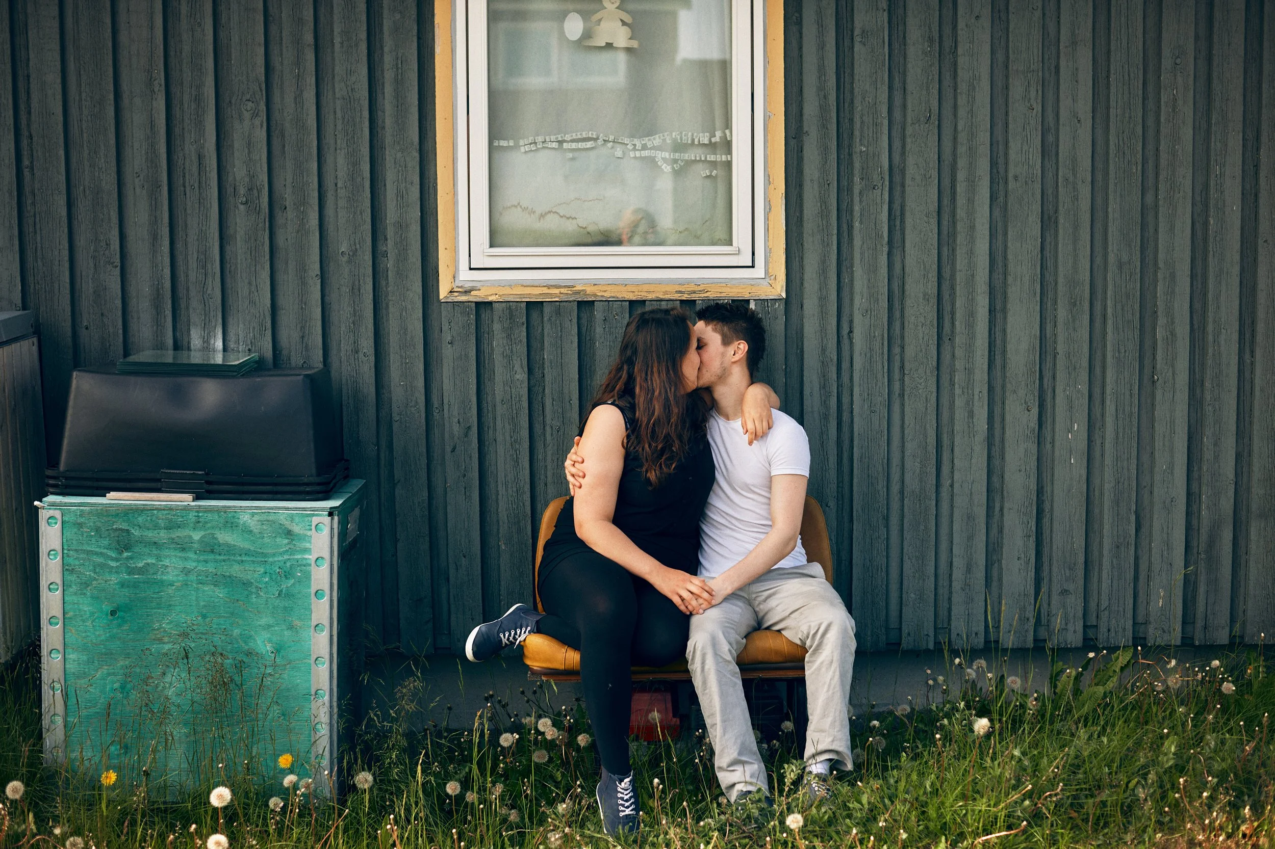 Couple sitting close together outside wooden house, intimate moment