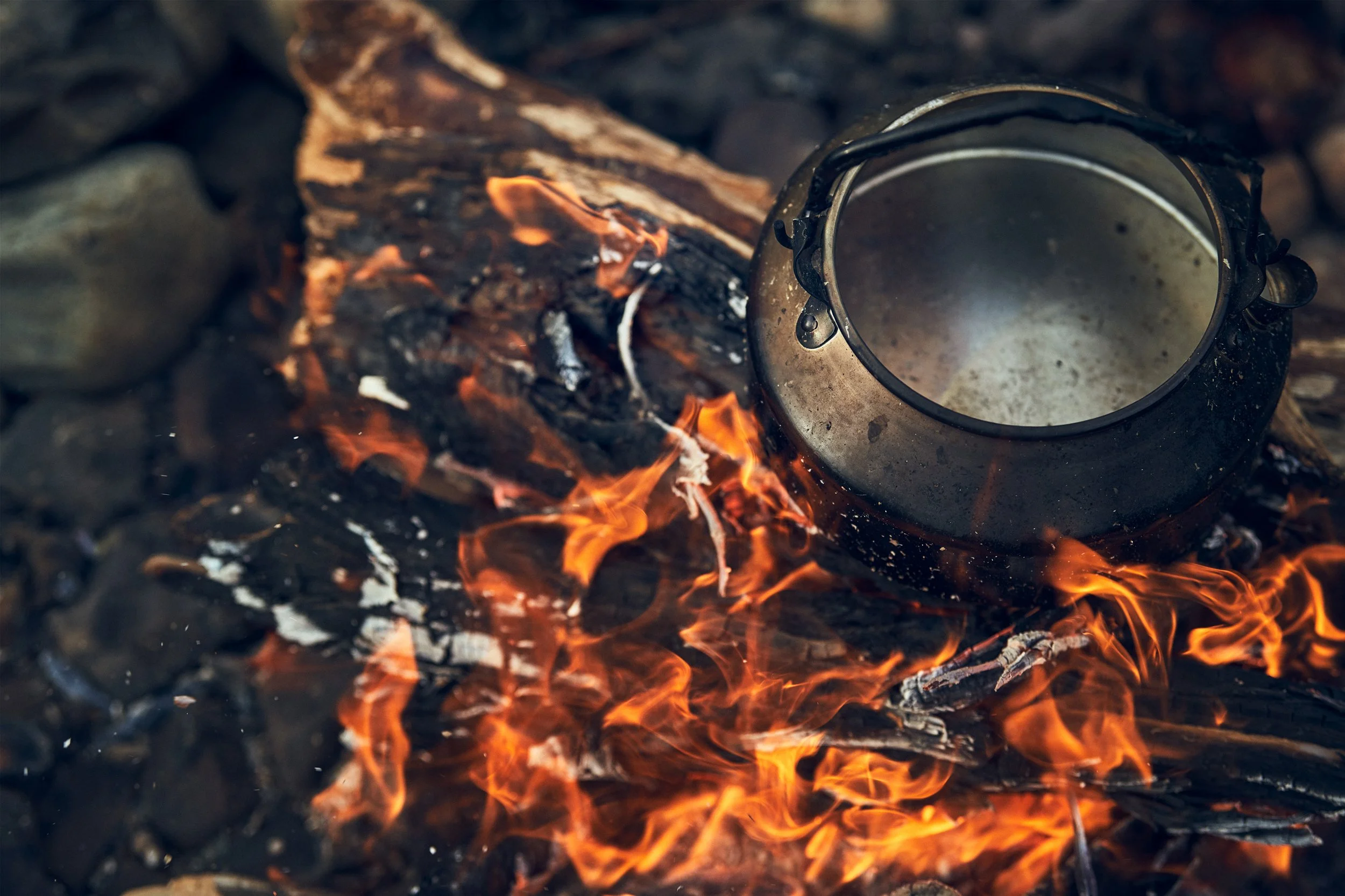 Metal kettle over open fire, outdoor cooking in cold environment
