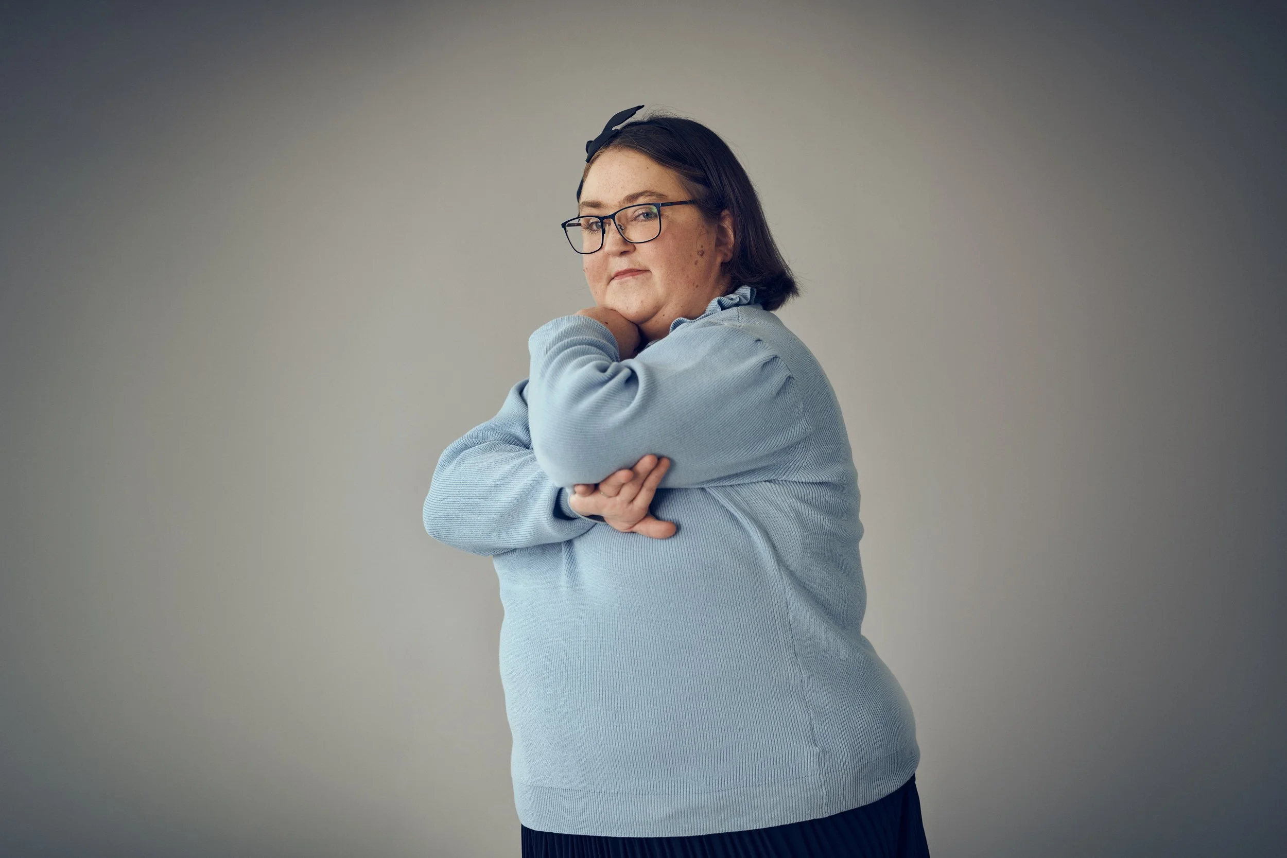 Portrait of woman standing with arms crossed, calm and composed expression