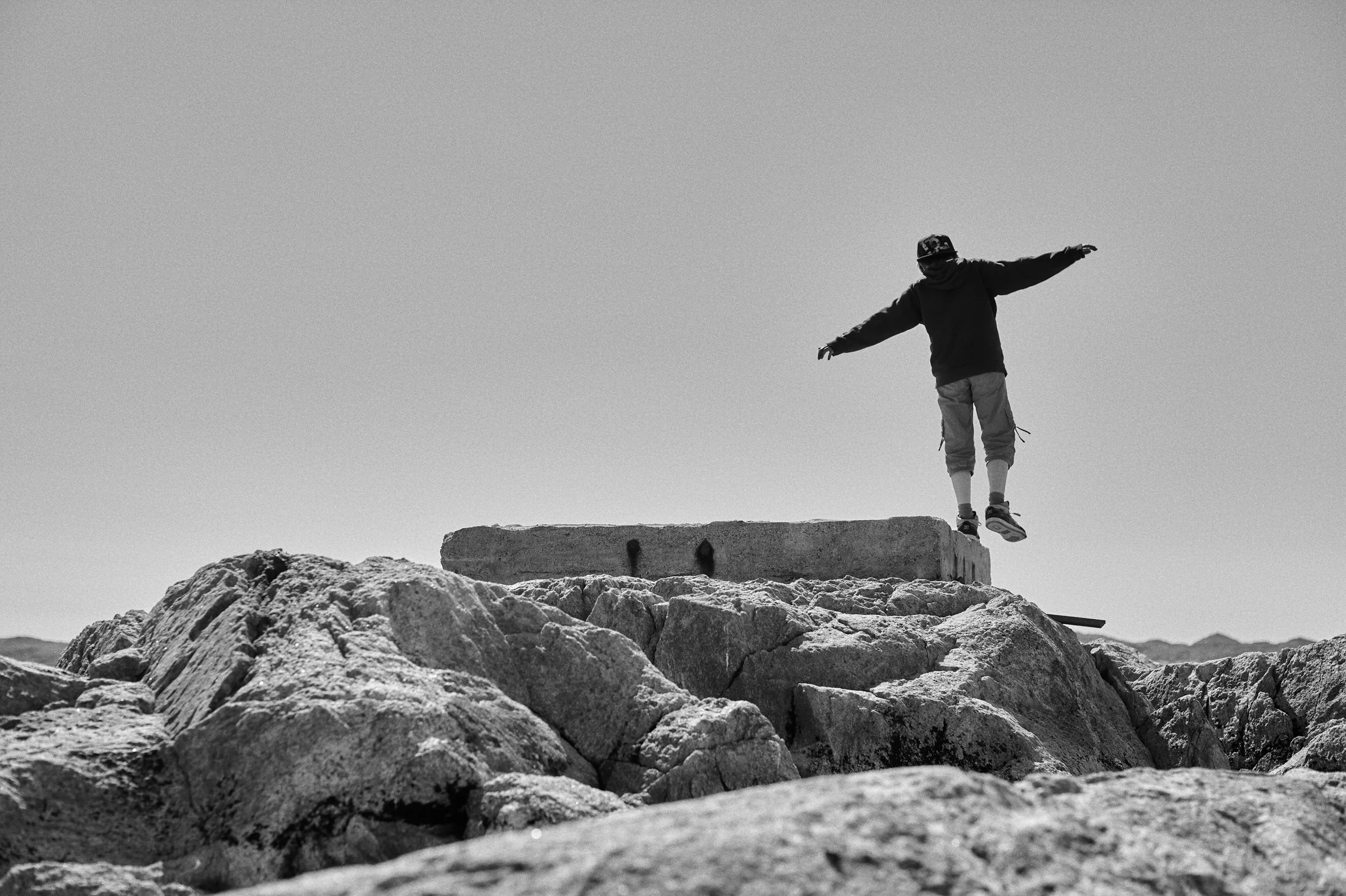 Kid balancing on rock formation with arms outstretched, solitary moment in open landscape