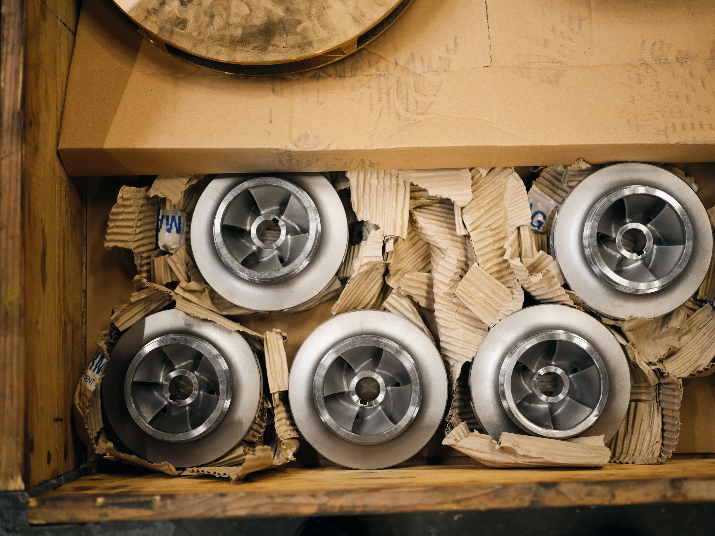 Close-up of metal components packed in cardboard, stacked in wooden crate