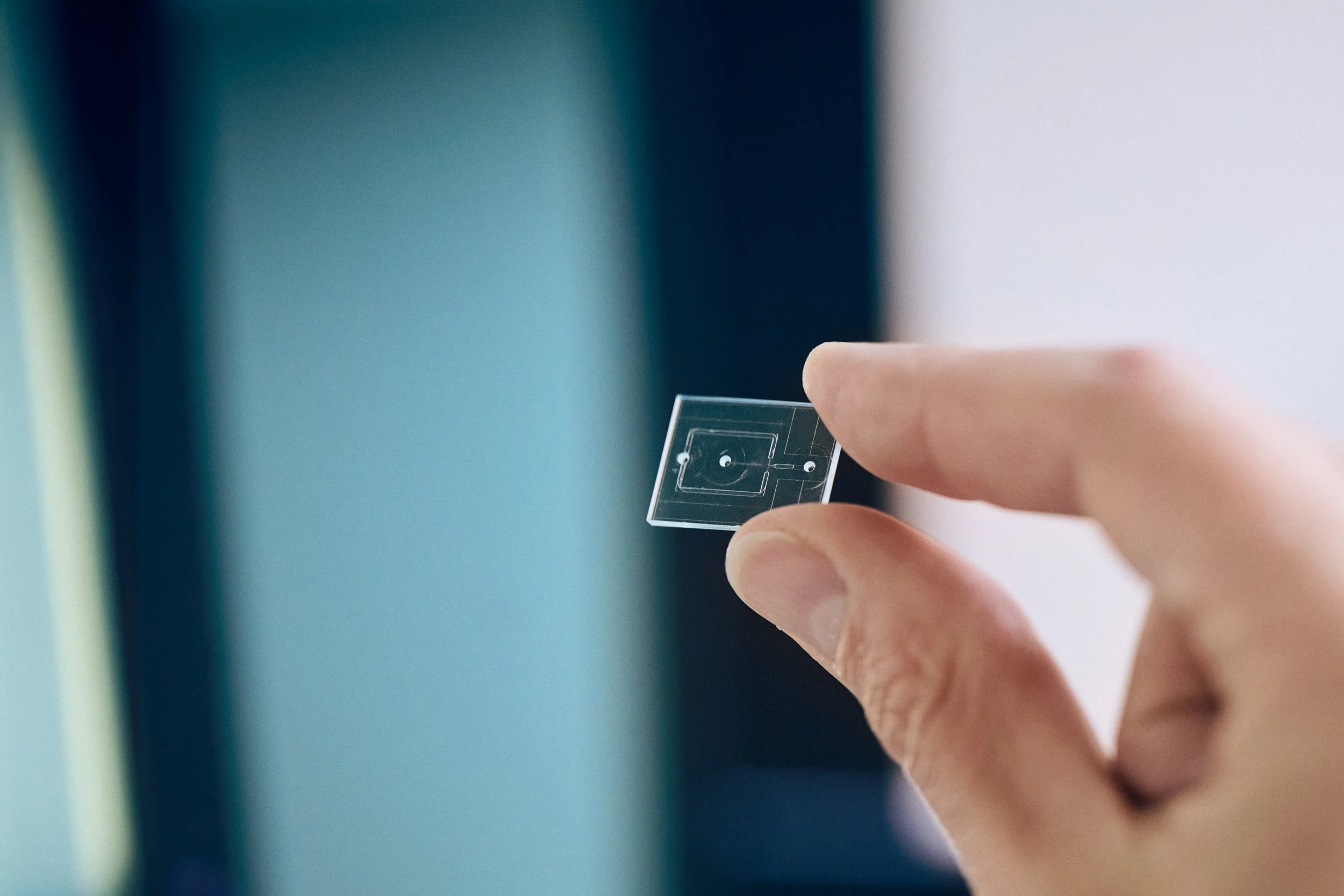Hand holding micro-scale sample slide, focusing on precision and detail in development process