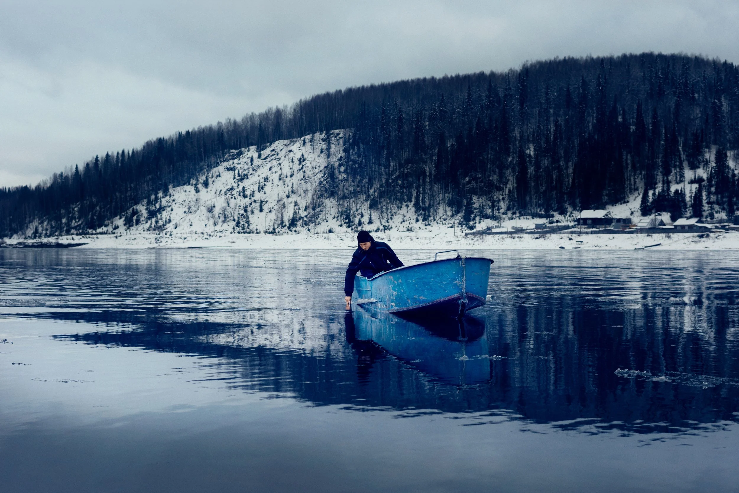 Person sailing in calm river, winter environment and solitary task