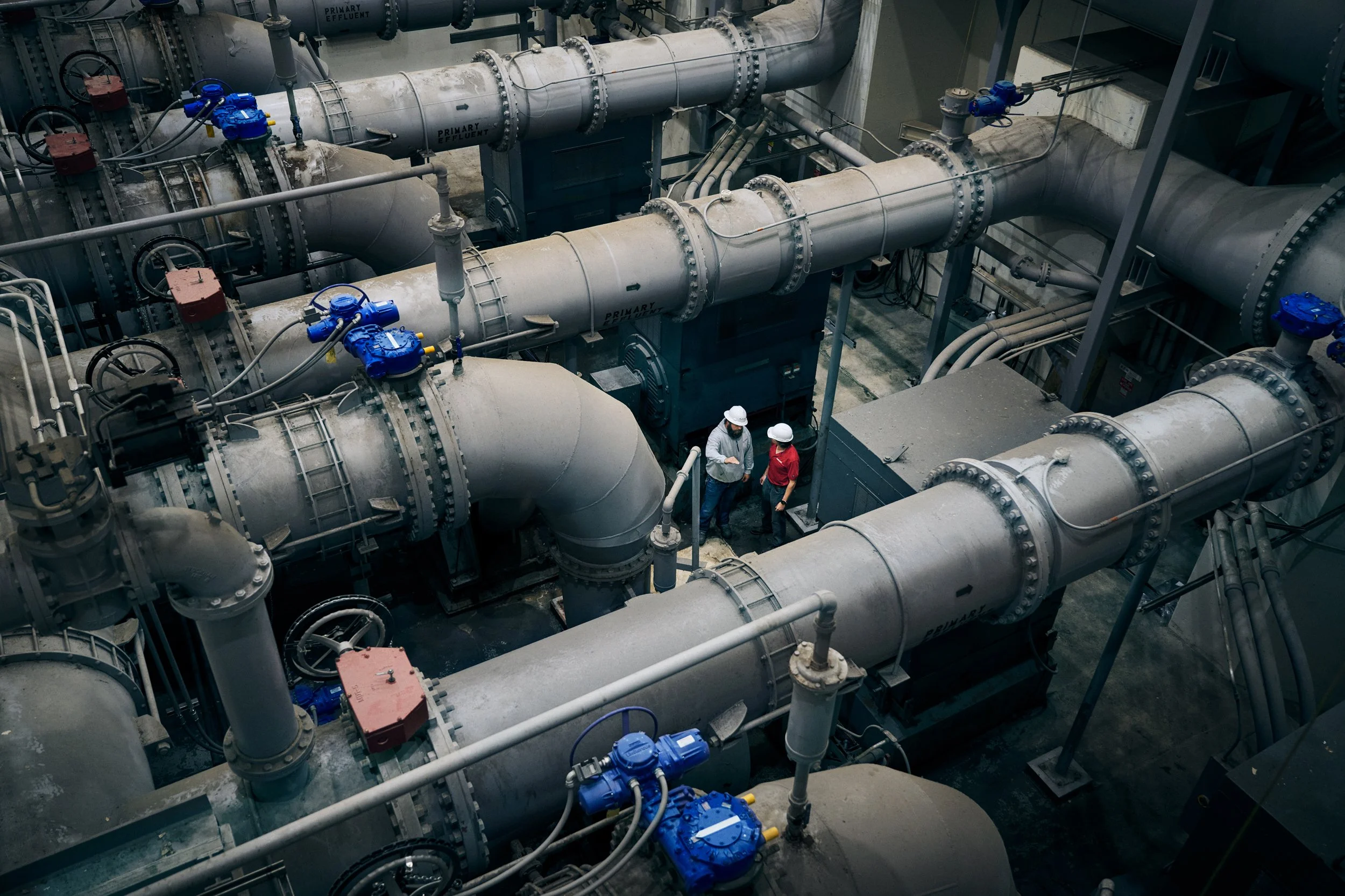Two workers standing inside large industrial pipe installation system