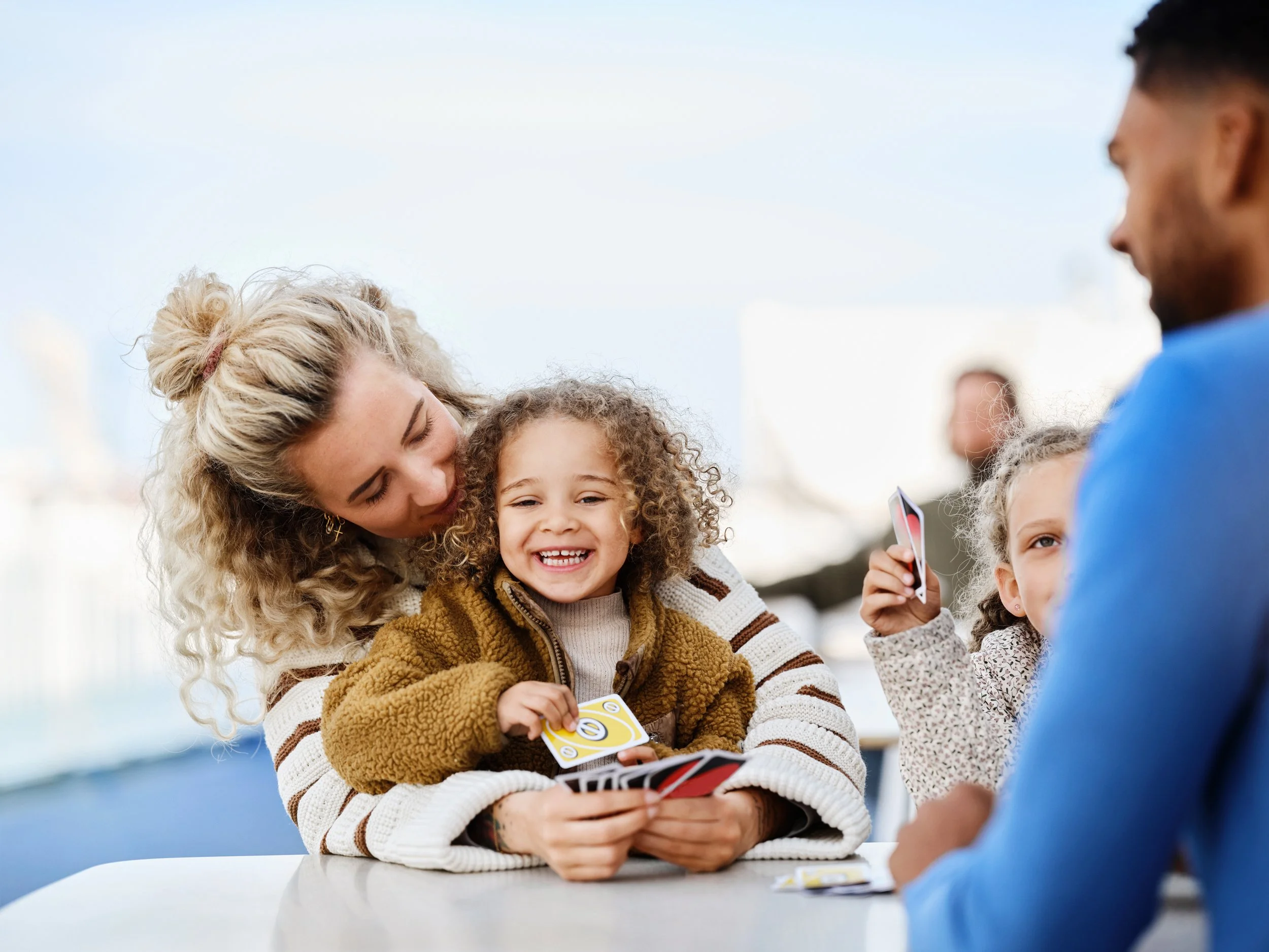 Family playing card game at table onboard ferry, social interaction during travel