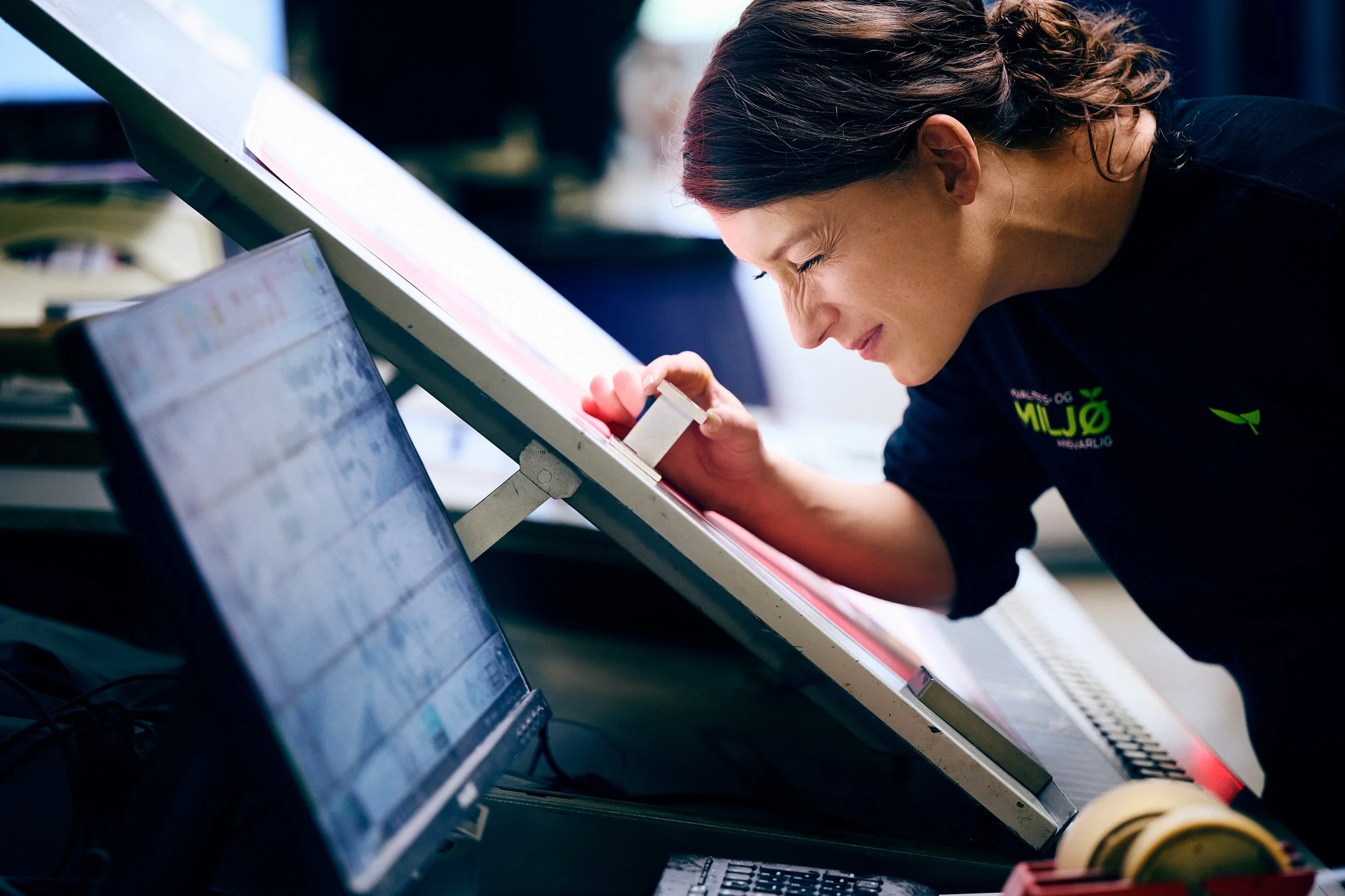 Worker examining material closely at workstation, precision and focus