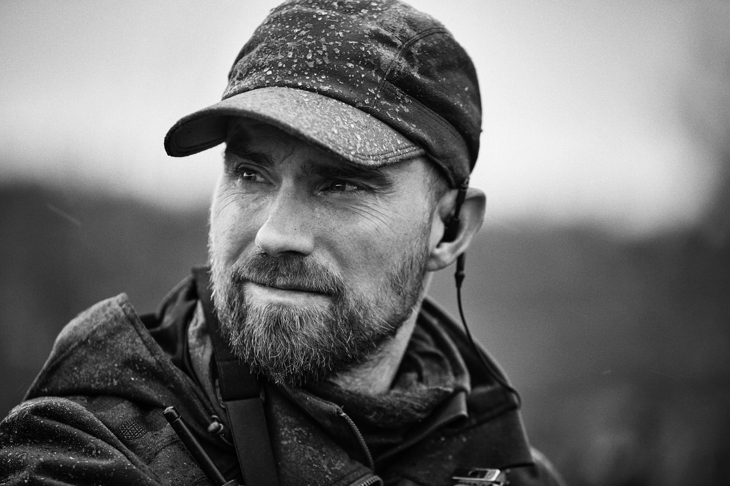 Portrait of hunter in outdoor environment, rain visible on clothing and cap