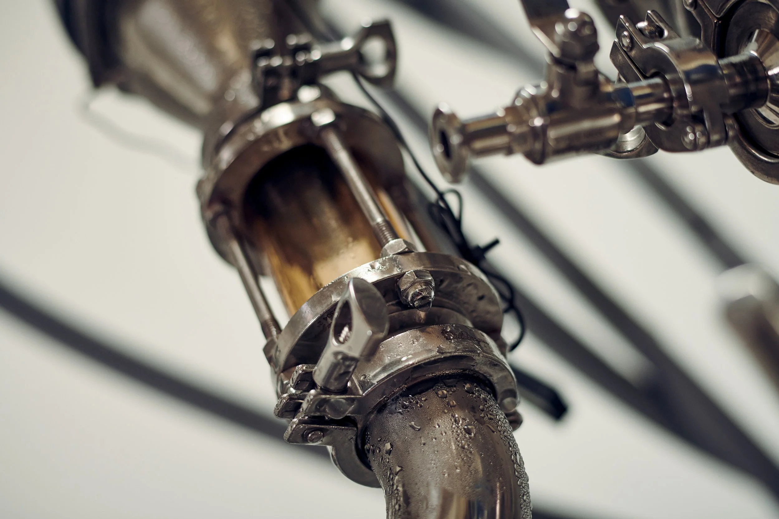 Close-up of liquid moving through glass section of distillation equipment, flow detail