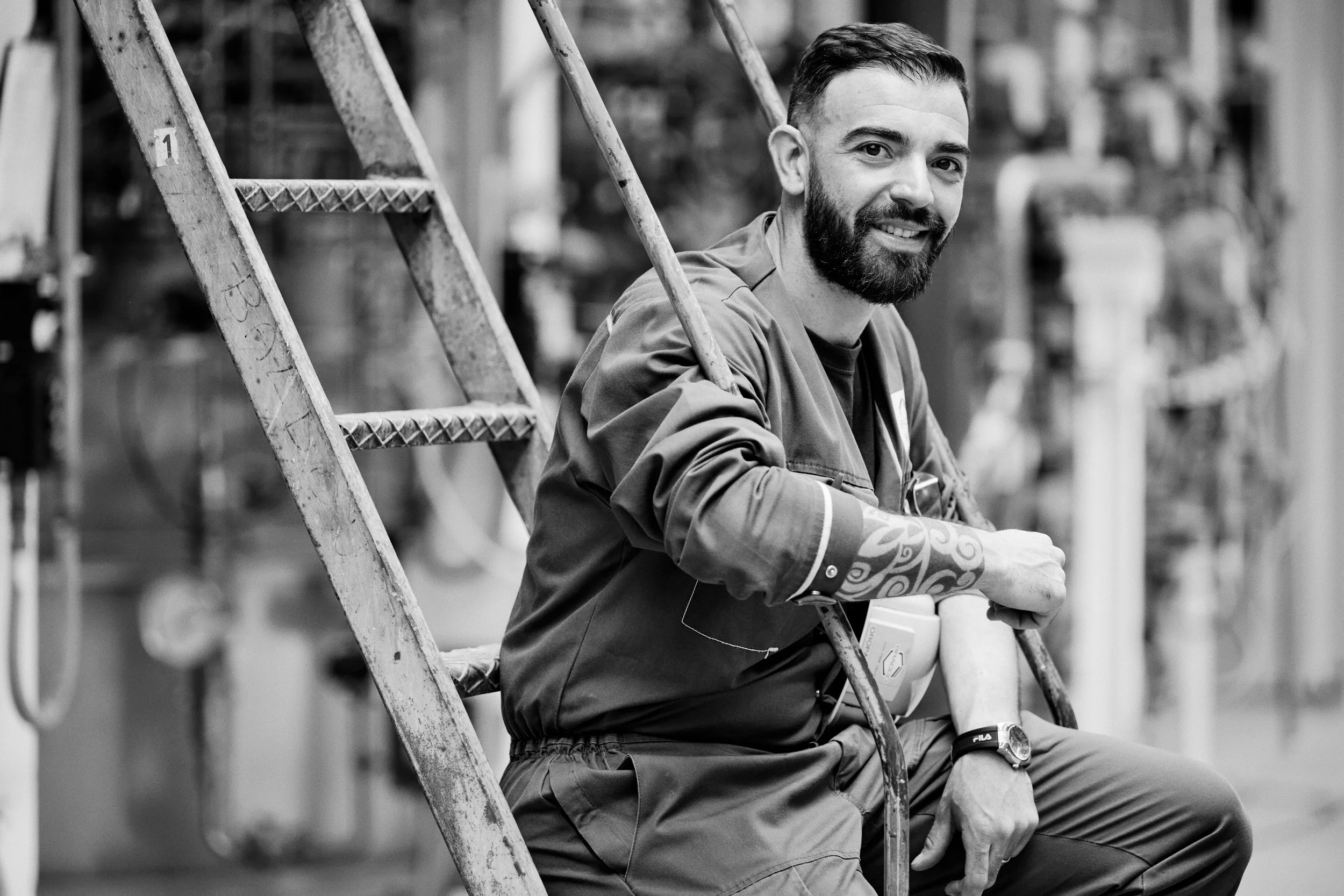Portrait of technician seated on industrial stairs within facility structure