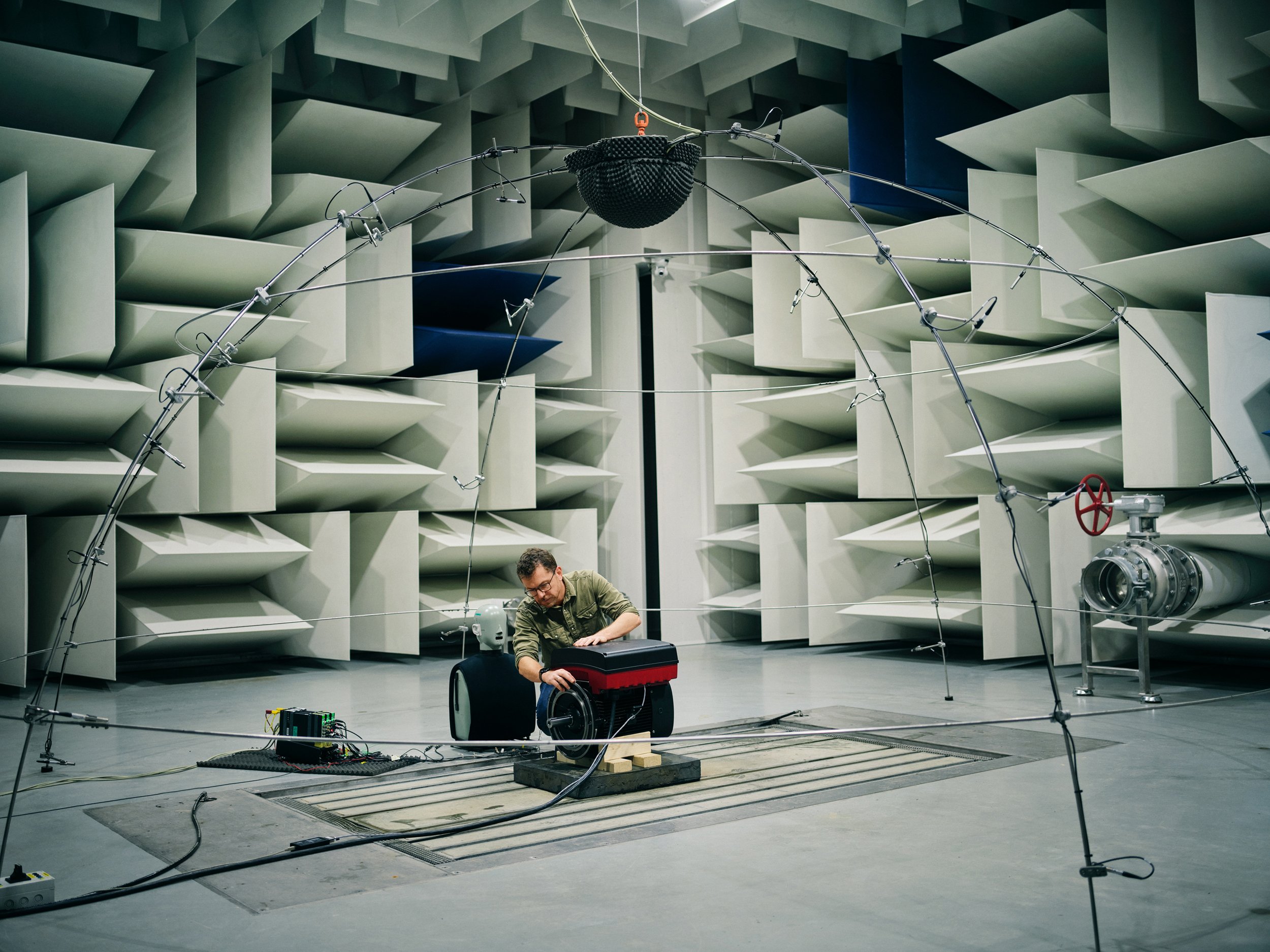 Technician setting up equipment in acoustic test chamber with sound-dampening structures