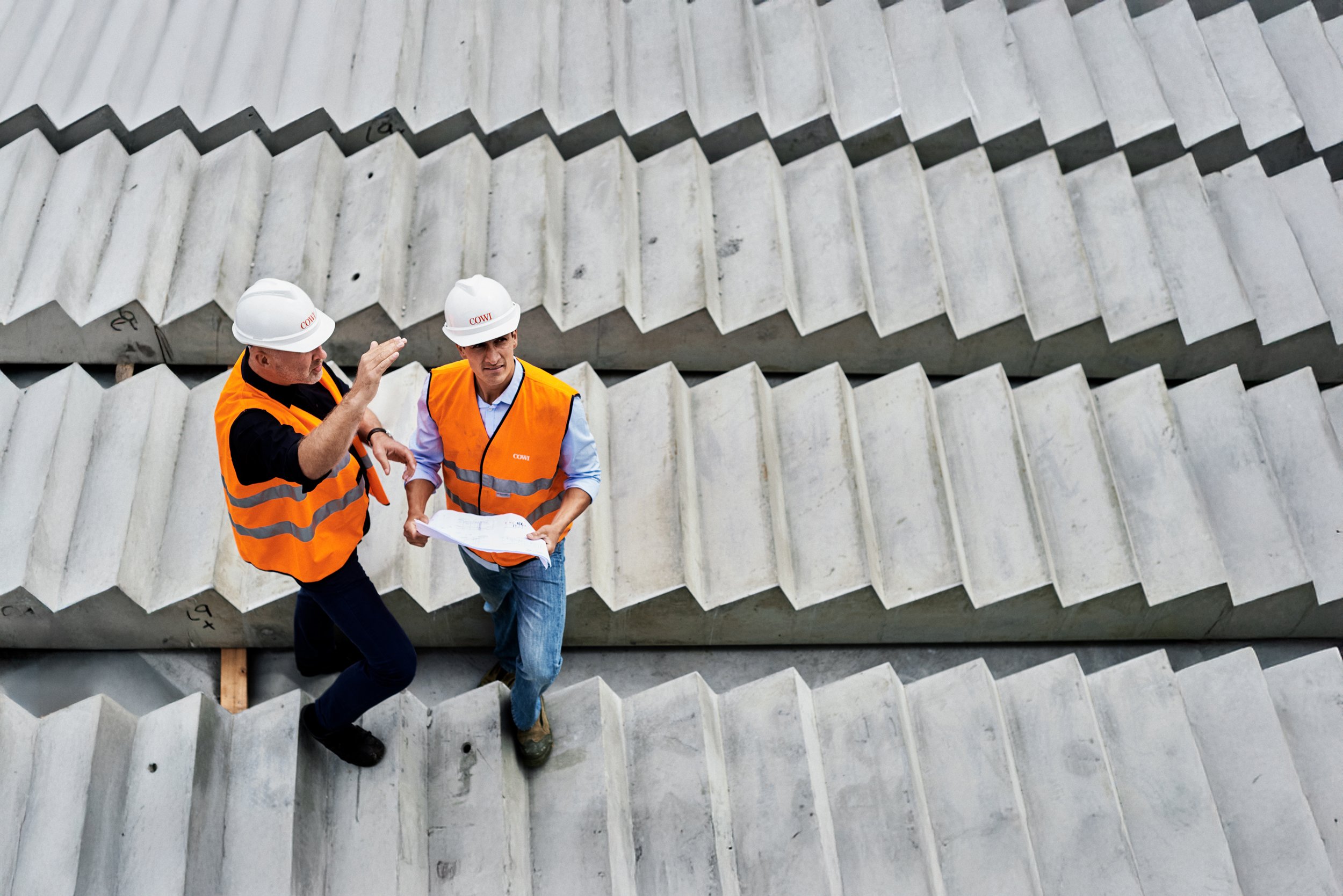Two engineers walking on concrete structure discussing plans