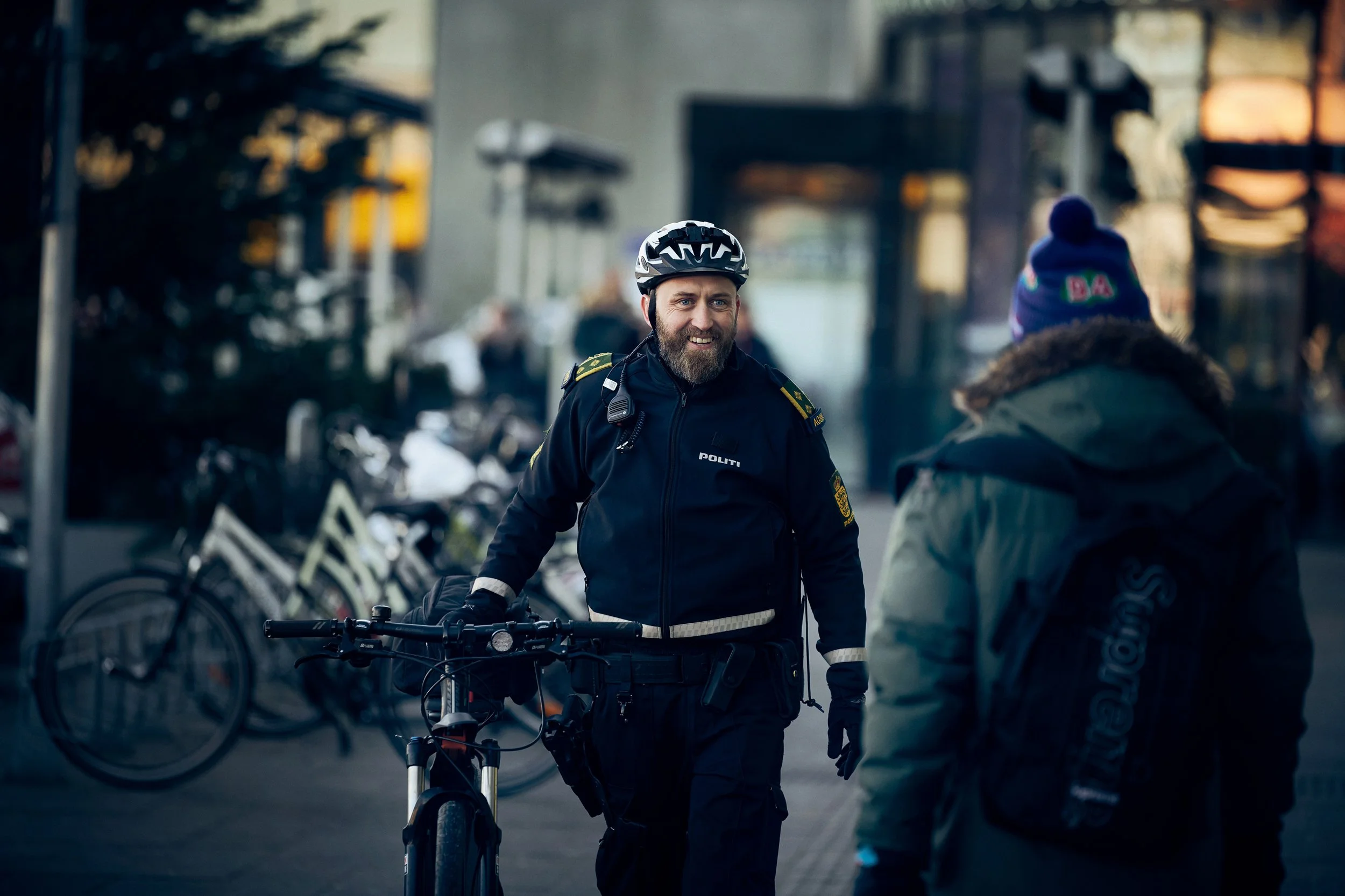 Police officer walking with bicycle in urban street